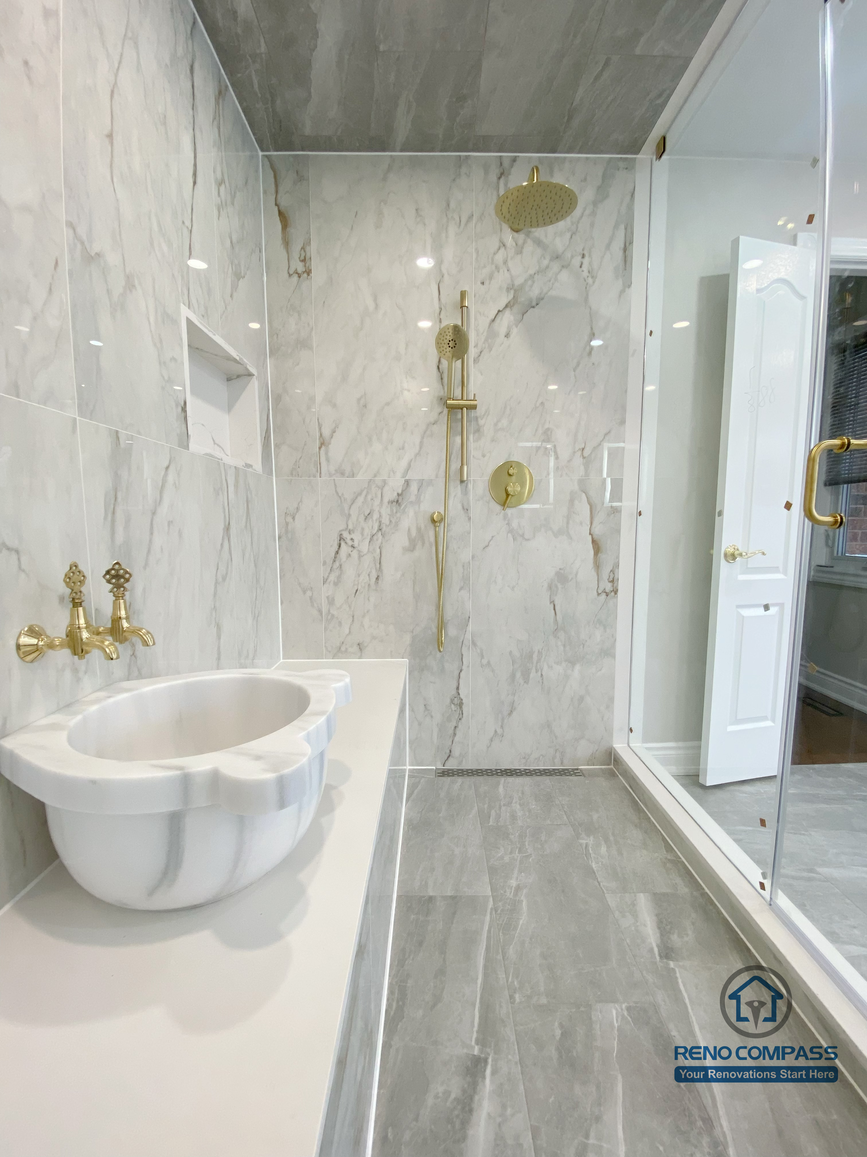 This Richmond Hill bathroom renovation showcases a bright and elegant design featuring a frameless glass shower enclosure, built-in bathtub, marble-style wall tiles, and gold-finish fixtures. The custom white vanity with integrated lighting mirror and large-format floor tiles enhance both functionality and visual openness. This project reflects high-quality craftsmanship and thoughtful layout planning for a modern bathroom renovation in Richmond Hill.