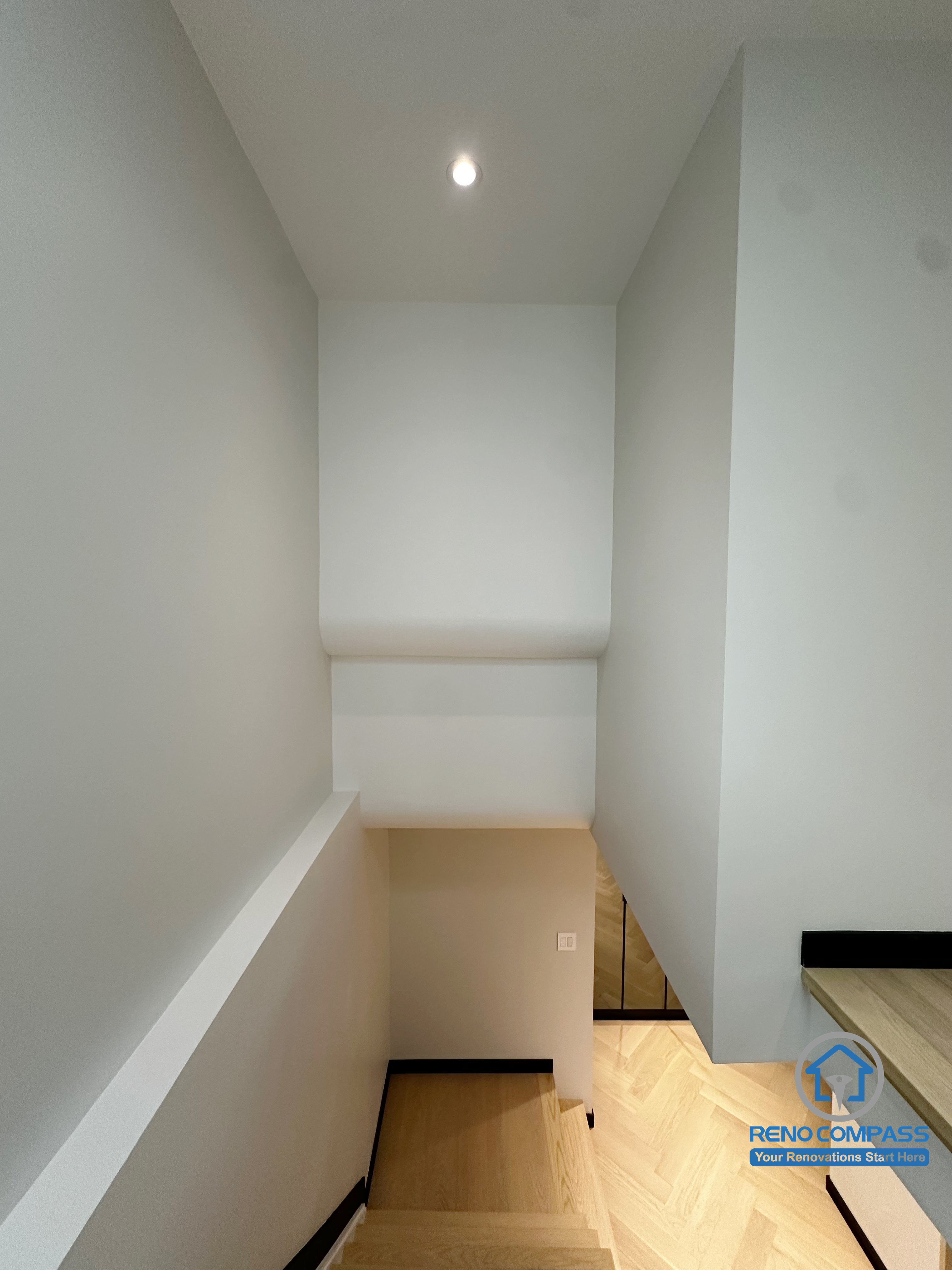 This image showcases the stairway corner from the Richmond Hill renovation project.
The clean white walls paired with light herringbone flooring create a bright and extended visual effect.
Black baseboards add structured contrast, enhancing the modern and minimal design language.