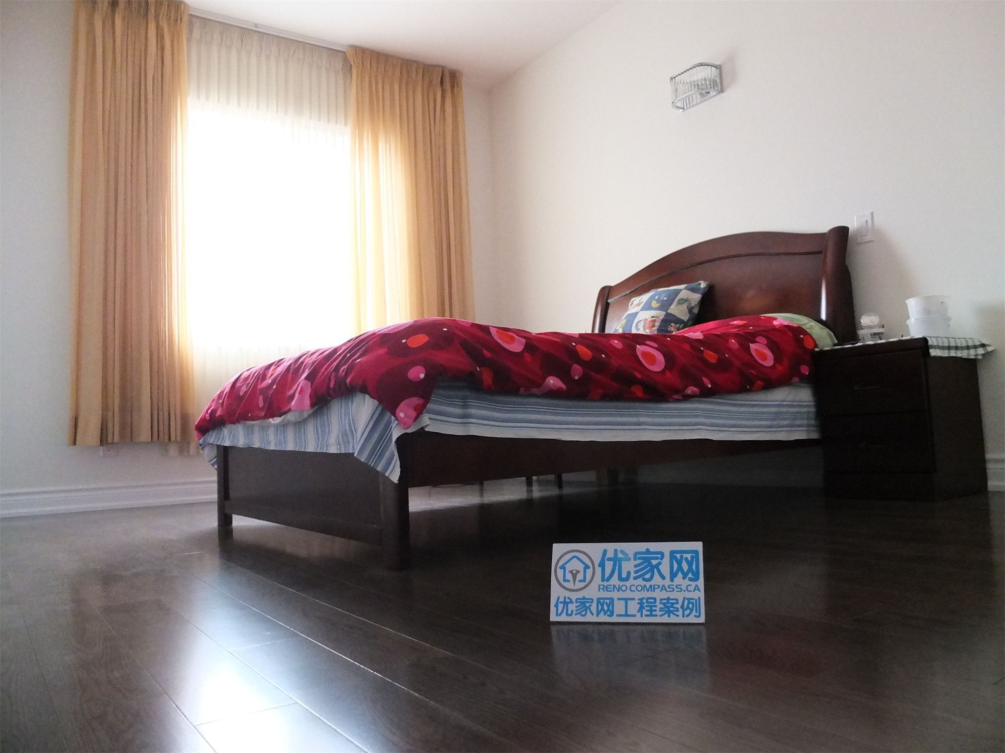 Bright bedroom space in a Scarborough home addition project featuring newly installed dark hardwood flooring, large window with natural light, and upgraded interior finishes. The renovation creates a comfortable and modern living environment within the expanded home layout.