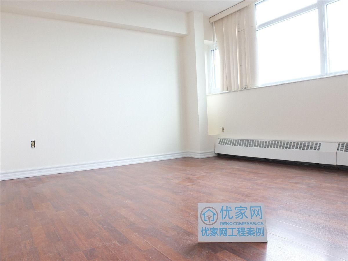 A bright and refreshed condo interior in Scarborough featuring newly installed flooring and clean white walls. This open living space benefits from large windows that enhance natural light, creating a warm and comfortable atmosphere. The renovation improves overall functionality and visual appeal, showcasing professional interior renovation work by a Toronto renovation company.