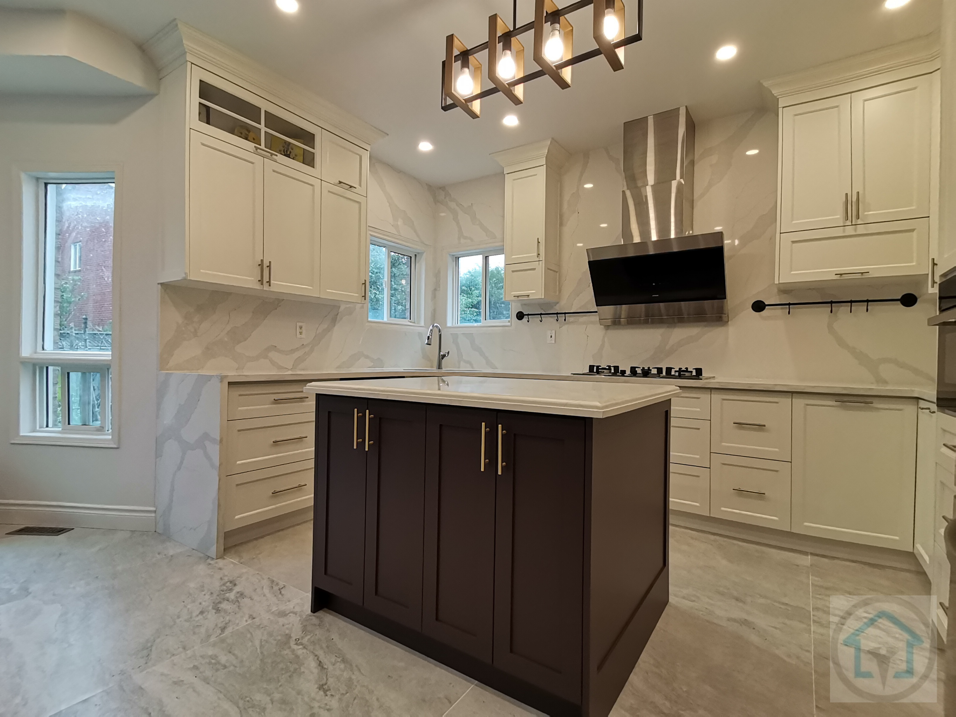 This bright white kitchen renovation showcases a clean, symmetrical layout centered around a statement dark-toned island. Full-height custom cabinetry, marble-look backsplash, and large-format floor tiles create a cohesive and upscale visual flow while enhancing light reflection throughout the space. The central island anchors the kitchen with added storage and prep space, making it ideal for both daily use and entertaining. Stainless steel appliances, integrated lighting, and a modern range hood complete the design with a balance of functionality and elegance. Completed by an experienced Toronto renovation company, this kitchen renovation highlights thoughtful planning, refined material selection, and long-term livability for modern family homes.