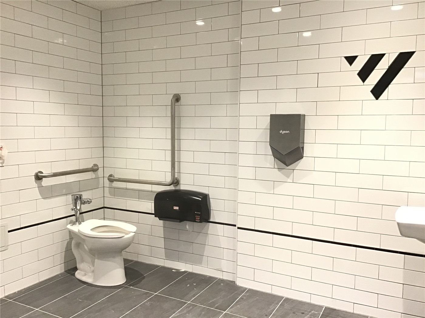 Accessible commercial washroom renovation in downtown Toronto featuring a barrier-free toilet, safety grab bars, and durable tile finishes, designed to meet accessibility standards and ensure comfort in high-traffic business environments.