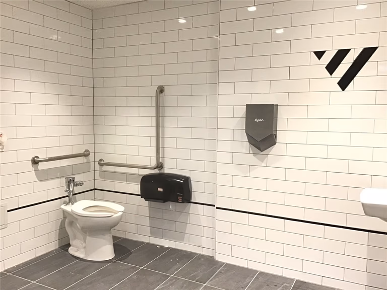 Accessible commercial washroom renovation in downtown Toronto featuring a barrier-free toilet, safety grab bars, and durable tile finishes, designed to meet accessibility standards and ensure comfort in high-traffic business environments.