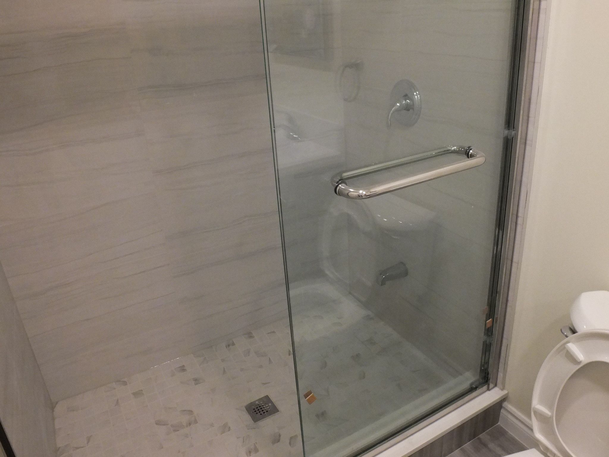 This Vaughan basement bathroom renovation features a sleek frameless glass shower enclosure designed for durability and modern aesthetics. Completed by a professional Toronto Renovation Company, the shower includes waterproof tile finishes, a secure glass door handle, and a clean linear layout that maximizes space and comfort. The contemporary design enhances brightness while maintaining easy maintenance and long-term functionality. This upgraded shower area adds both style and value to the finished basement bathroom, making it ideal for everyday use and guest convenience.