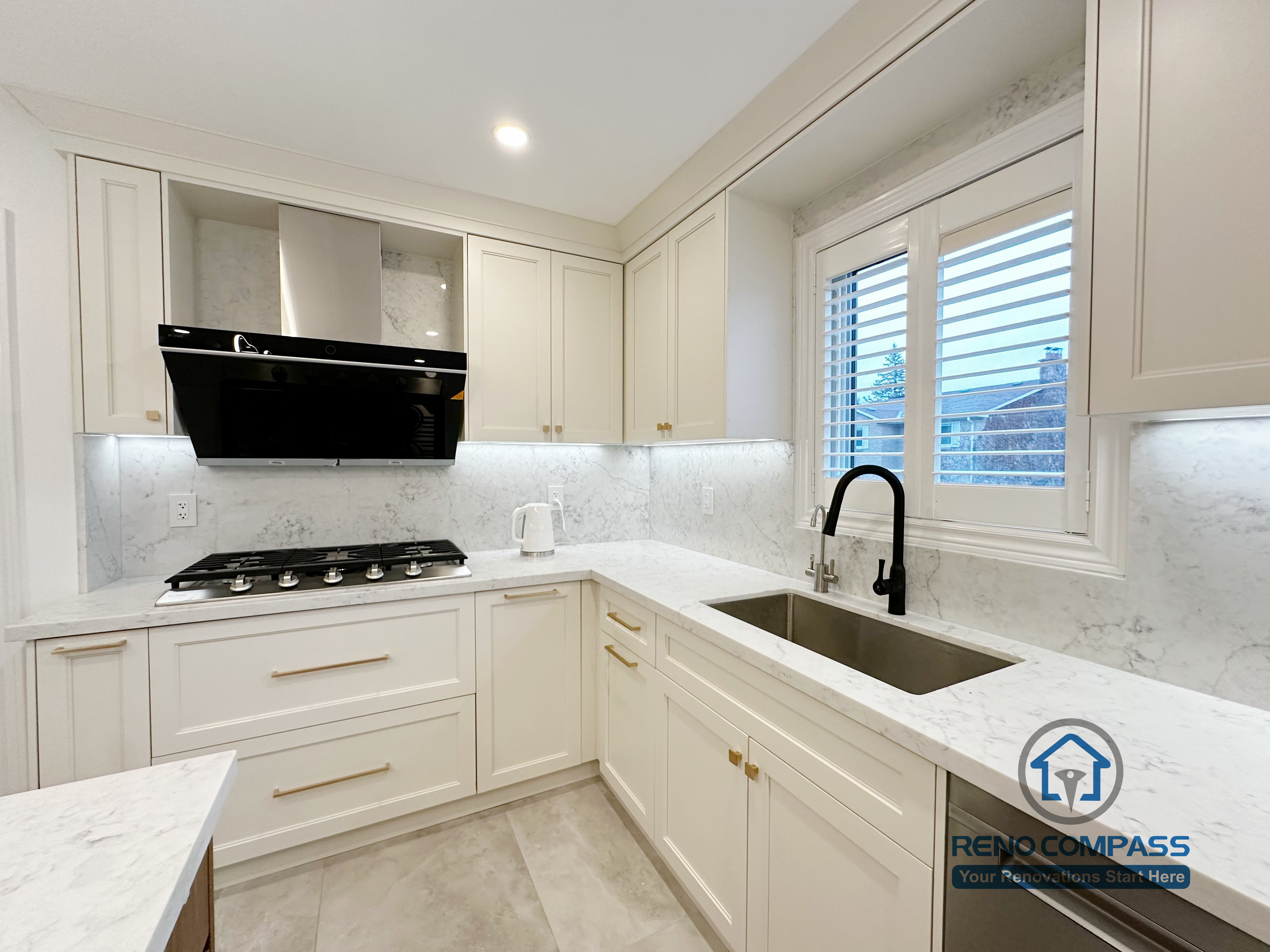 This Markham kitchen renovation features custom white cabinetry paired with quartz countertops and a clean, functional layout. The L-shaped design improves workflow efficiency while maintaining visual balance and brightness. Integrated under-cabinet lighting enhances task visibility, and the contrast between the black range hood and brass hardware adds subtle character to the space. Designed and completed by a professional Toronto renovation company, this kitchen reflects precision craftsmanship, durable materials, and long-term usability for everyday living.