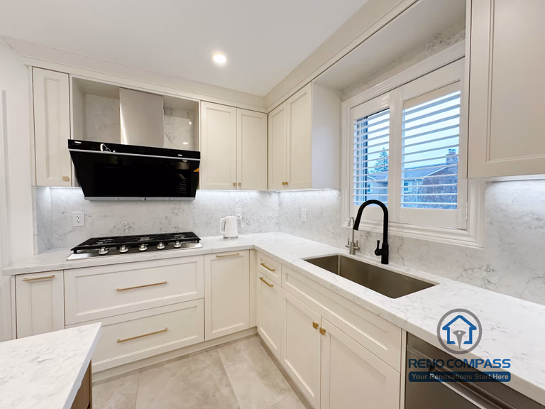 This Markham kitchen renovation features custom white cabinetry paired with quartz countertops and a clean, functional layout. The L-shaped design improves workflow efficiency while maintaining visual balance and brightness. Integrated under-cabinet lighting enhances task visibility, and the contrast between the black range hood and brass hardware adds subtle character to the space. Designed and completed by a professional Toronto renovation company, this kitchen reflects precision craftsmanship, durable materials, and long-term usability for everyday living.