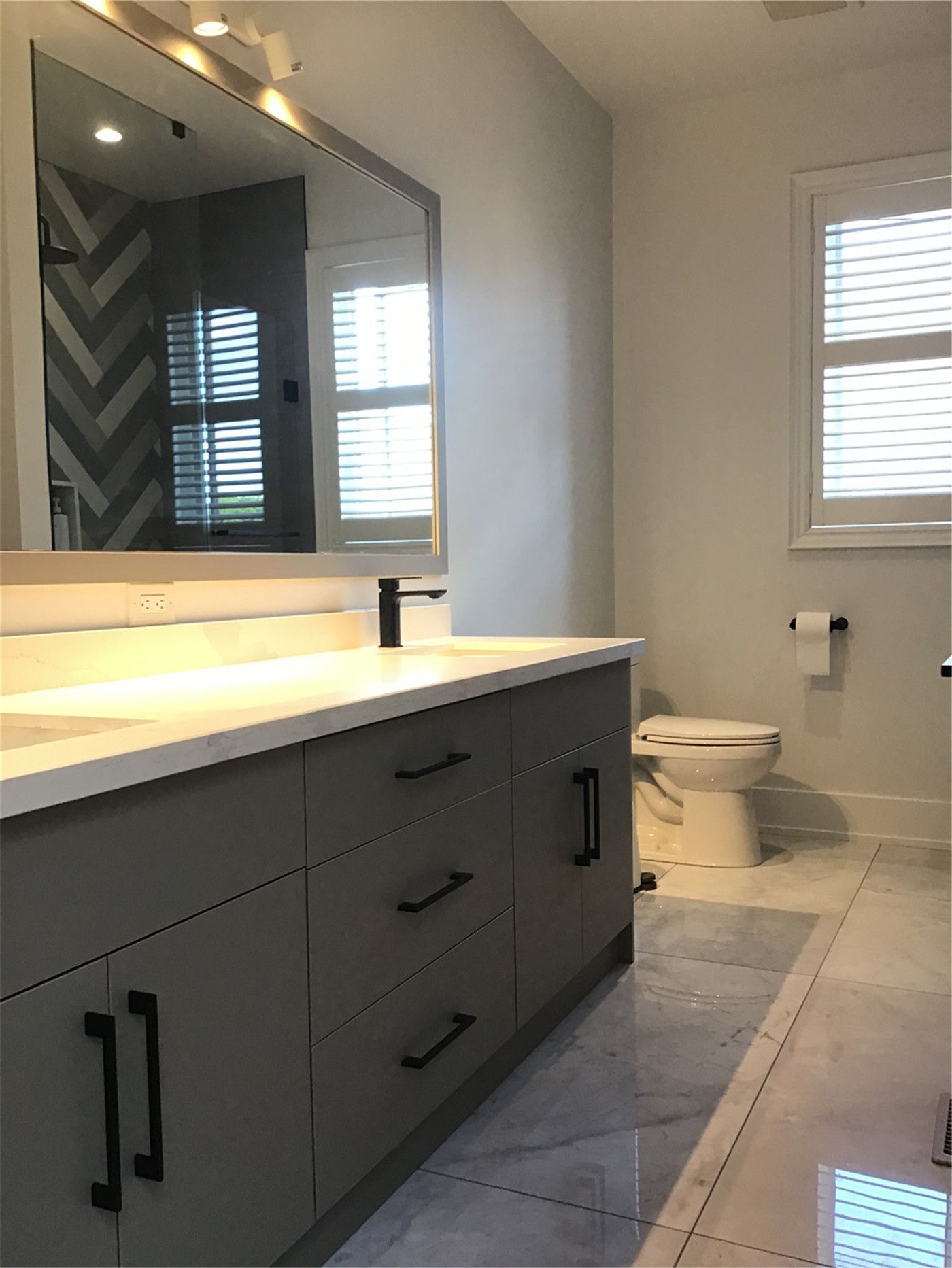 This Markham full home renovation features a sleek and contemporary bathroom with a custom grey vanity, integrated LED mirror lighting, and polished tile flooring. The clean layout, matte black fixtures, and soft ambient lighting create a refined and functional space. Completed by a professional Toronto Renovation Company, this bathroom design combines modern aesthetics with everyday practicality.
