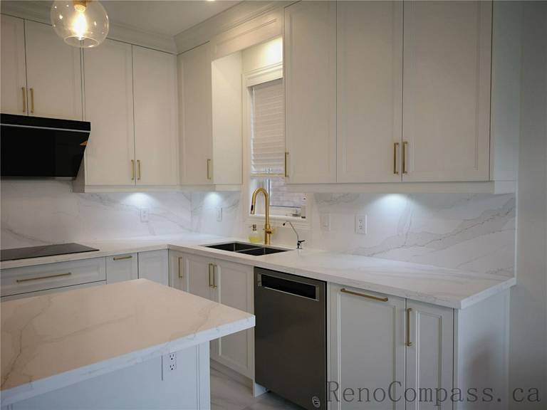 This Aurora kitchen renovation showcases a bright open-concept design featuring custom white shaker cabinets, quartz countertops, and a functional center island. Elegant pendant lighting, marble-style flooring, and brushed gold fixtures add warmth and sophistication to the modern space. Completed by a professional Toronto renovation company focused on quality craftsmanship, efficient layout planning, and timeless interior design.