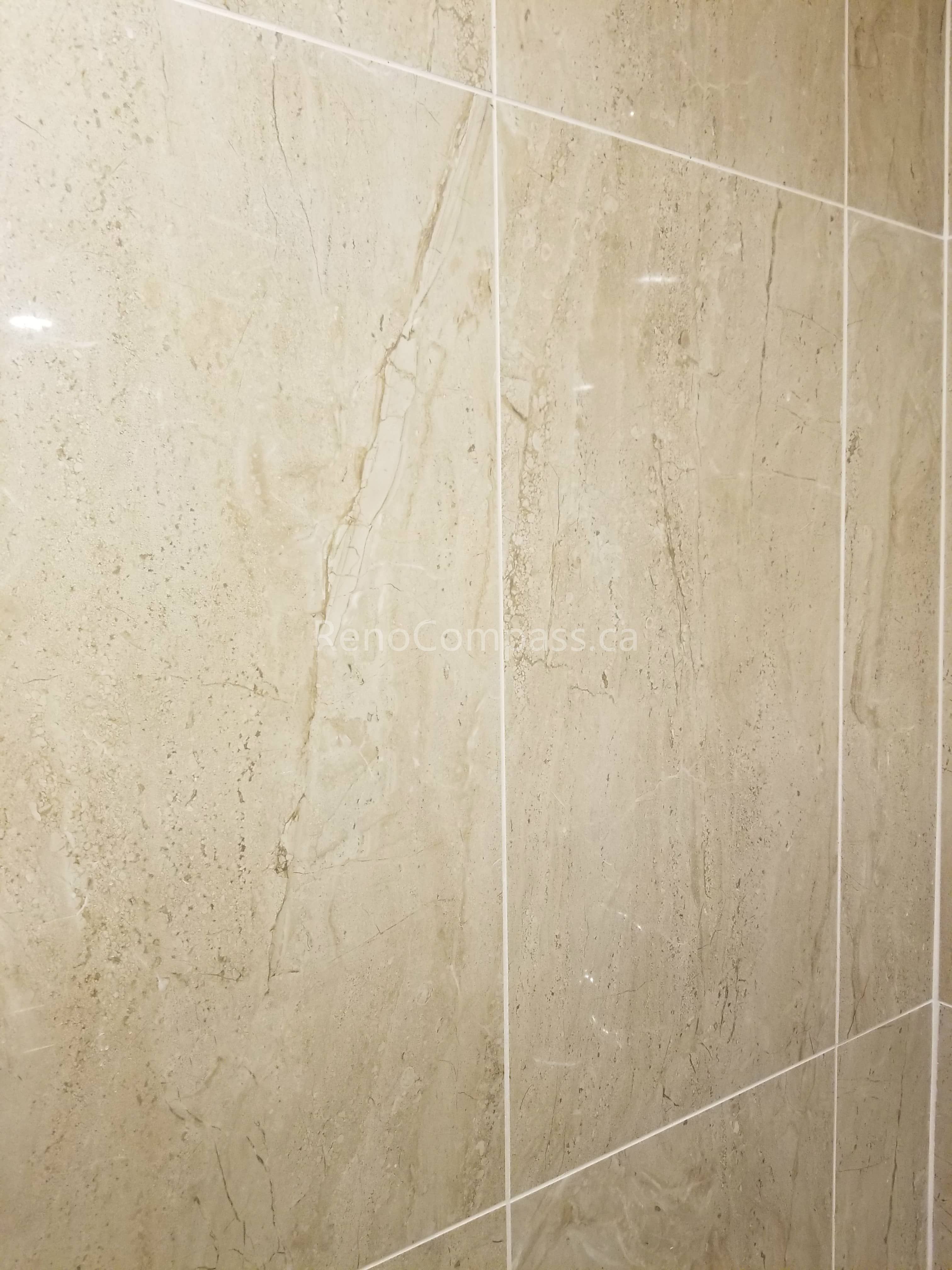 This Vaughan basement bathroom renovation highlights premium beige marble-look wall tile installation, creating a clean, elegant, and moisture-resistant shower environment. The large-format tiles and precise grout lines deliver a seamless modern finish while improving durability and easy maintenance. Professionally completed by Reno Compass Inc., this detailed tile work enhances both the visual appeal and functionality of the upgraded basement bathroom space.