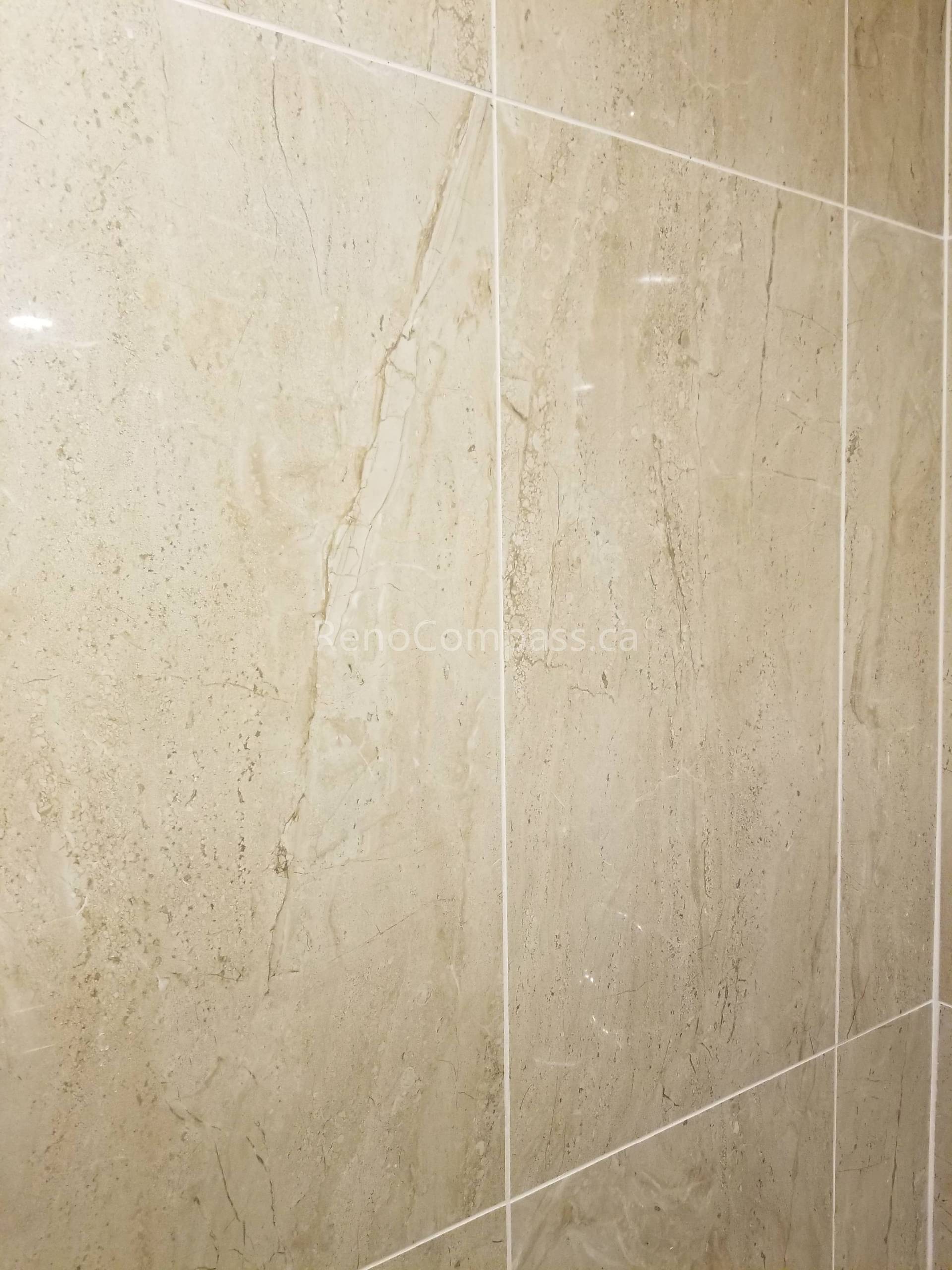 This Vaughan basement bathroom renovation highlights premium beige marble-look wall tile installation, creating a clean, elegant, and moisture-resistant shower environment. The large-format tiles and precise grout lines deliver a seamless modern finish while improving durability and easy maintenance. Professionally completed by Reno Compass Inc., this detailed tile work enhances both the visual appeal and functionality of the upgraded basement bathroom space.