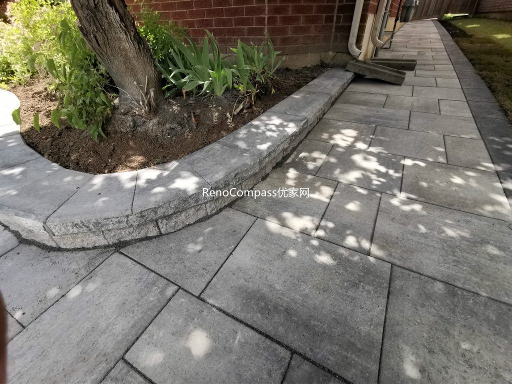 Beautifully finished side walkway interlocking project in Richmond Hill. The light gray stone pavers are neatly aligned against the house, featuring a raised garden border for a clean and modern look. Installed by Reno Compass for improved drainage, durability, and curb appeal.