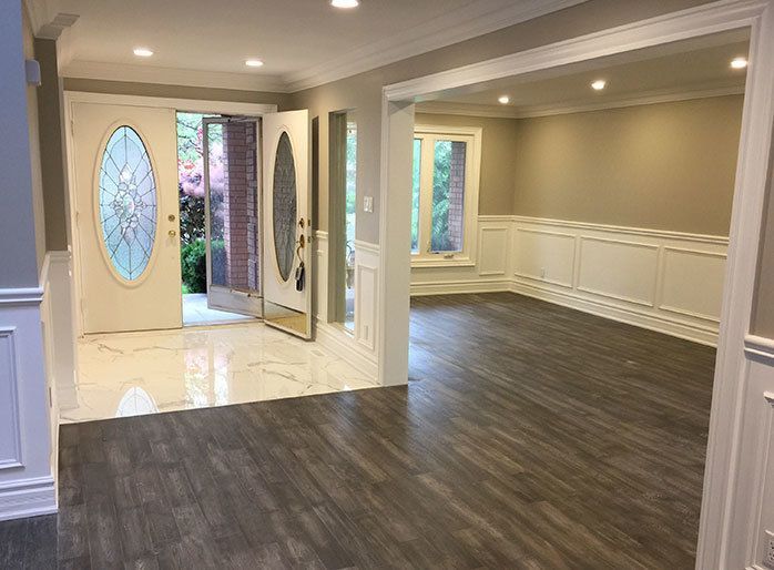 This Richmond Hill luxury house renovation showcases a bright open-concept living and entrance area featuring new flooring, modern wall panel detailing, and upgraded lighting. The redesigned space enhances flow, elegance, and functionality, creating a welcoming and refined interior that complements the home’s luxury style.