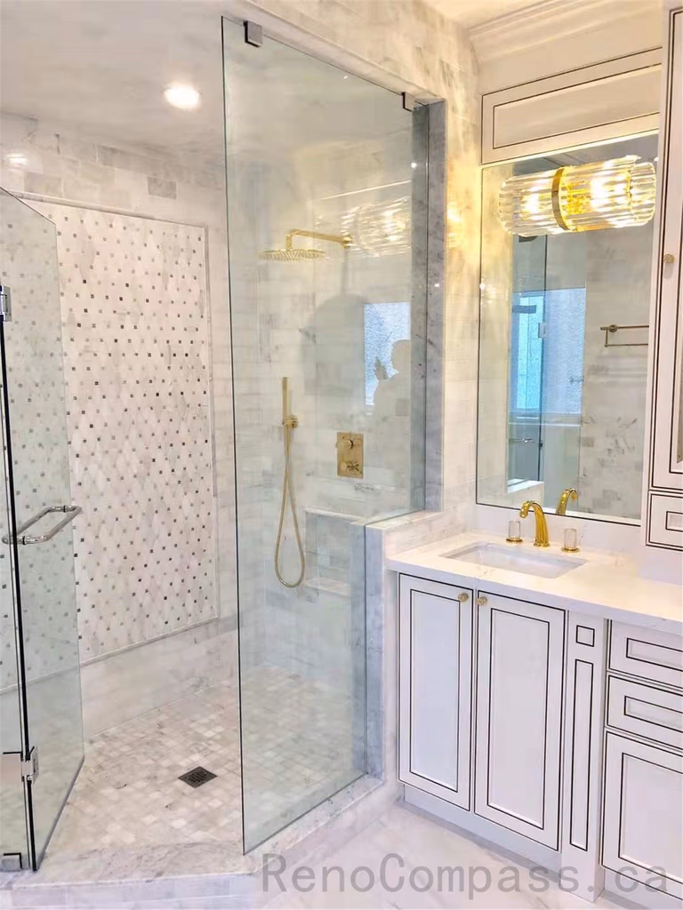 This North York bathroom renovation features a modern glass walk-in shower with marble-look wall tiles and mosaic accent details, paired with a custom vanity, quartz countertop, and elegant gold fixtures. The bright and refined layout enhances both functionality and luxury, creating a timeless and comfortable bathroom space. Completed by a professional Toronto renovation company specializing in high-end residential renovations.