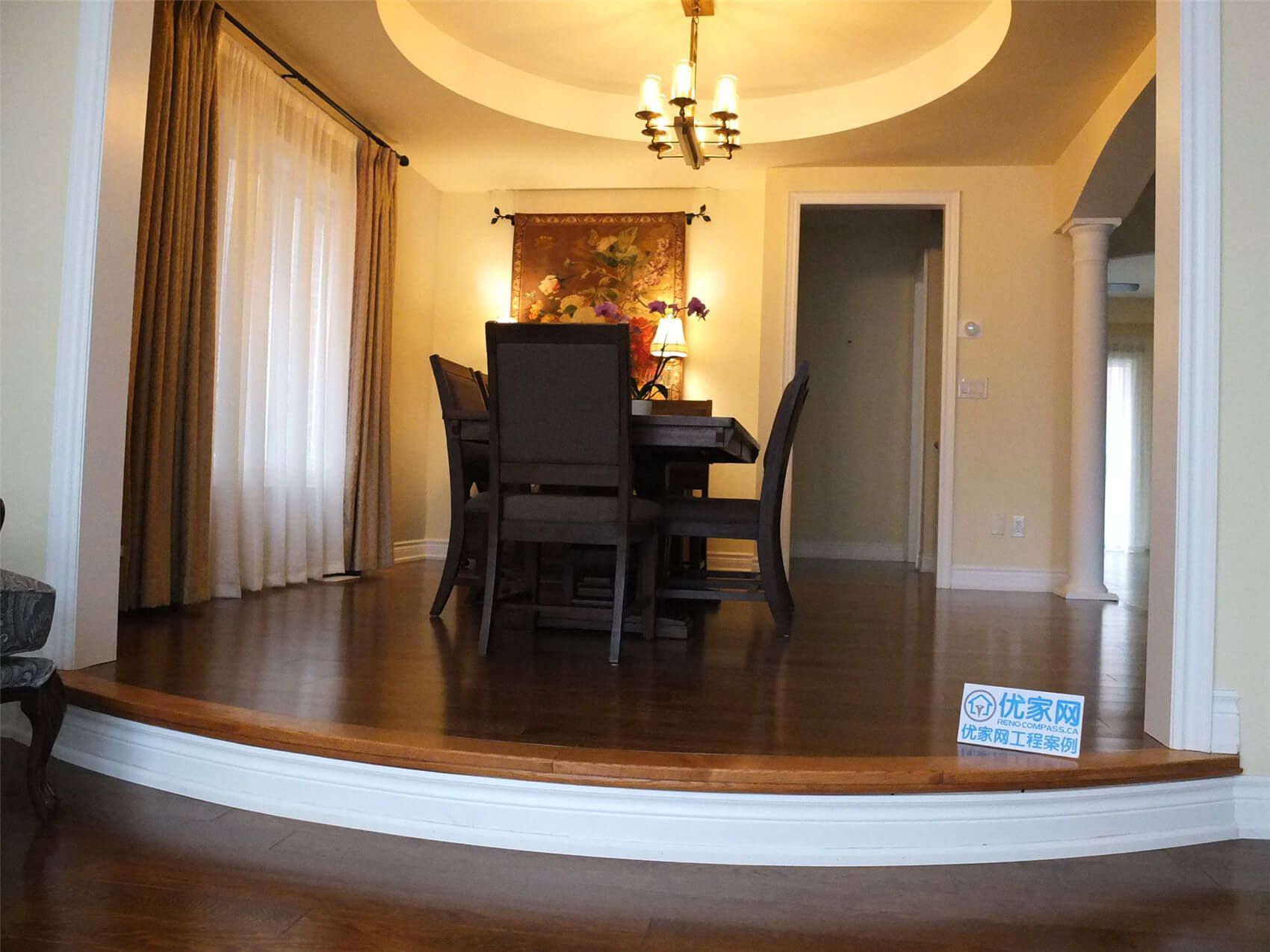 This Aurora flooring renovation highlights a beautifully upgraded dining room featuring rich hardwood flooring and elegant interior details. The polished wood floor complements the elevated dining area, curved step design, and warm ceiling lighting, creating a sophisticated and inviting atmosphere. Completed by a professional Toronto renovation company, the flooring installation enhances both the visual appeal and durability of this refined dining space.