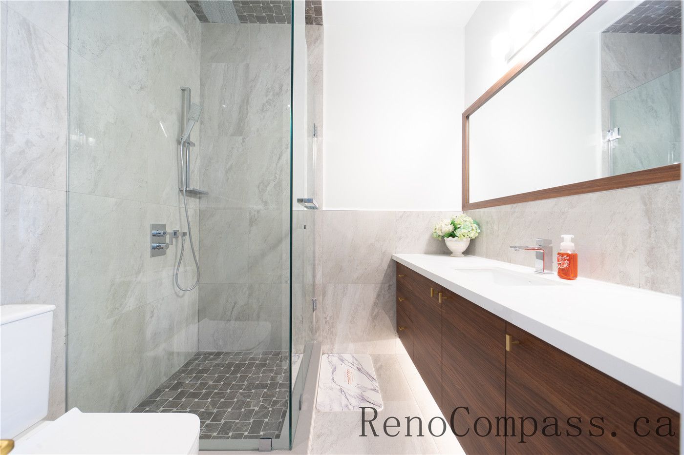 This Richmond Hill entire house interior renovation features a sleek modern bathroom with a frameless glass shower, large-format wall tiles, and a custom double vanity with quartz countertop. Clean lines, warm wood finishes, and integrated lighting create a bright and functional space designed for everyday comfort. Completed by a trusted Toronto renovation company, this bathroom renovation delivers durability, style, and long-term value.