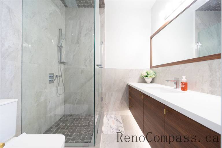 This Richmond Hill entire house interior renovation features a sleek modern bathroom with a frameless glass shower, large-format wall tiles, and a custom double vanity with quartz countertop. Clean lines, warm wood finishes, and integrated lighting create a bright and functional space designed for everyday comfort. Completed by a trusted Toronto renovation company, this bathroom renovation delivers durability, style, and long-term value.