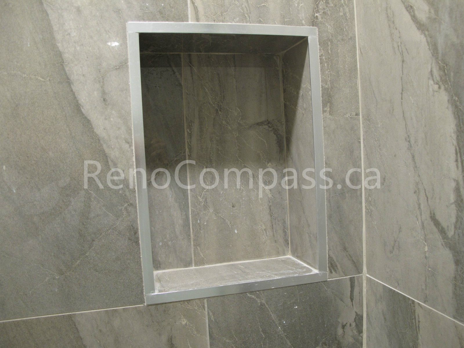 Built-in shower niche detail from a Markham basement renovation, finished with marble-look porcelain tiles and clean trim edges for a seamless storage solution. Completed by Reno Compass, this custom shower feature adds convenience, durability, and modern design to the upgraded basement bathroom.