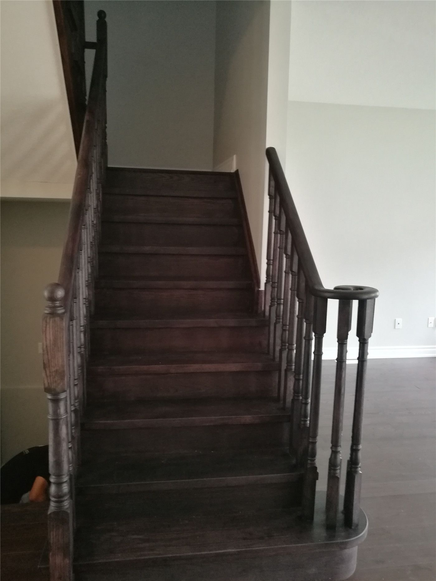 This image features a staircase after a Markham interior renovation, highlighting dark hardwood stair treads, upgraded wooden railings, and clean surrounding finishes that enhance both safety and visual continuity with the main living area.