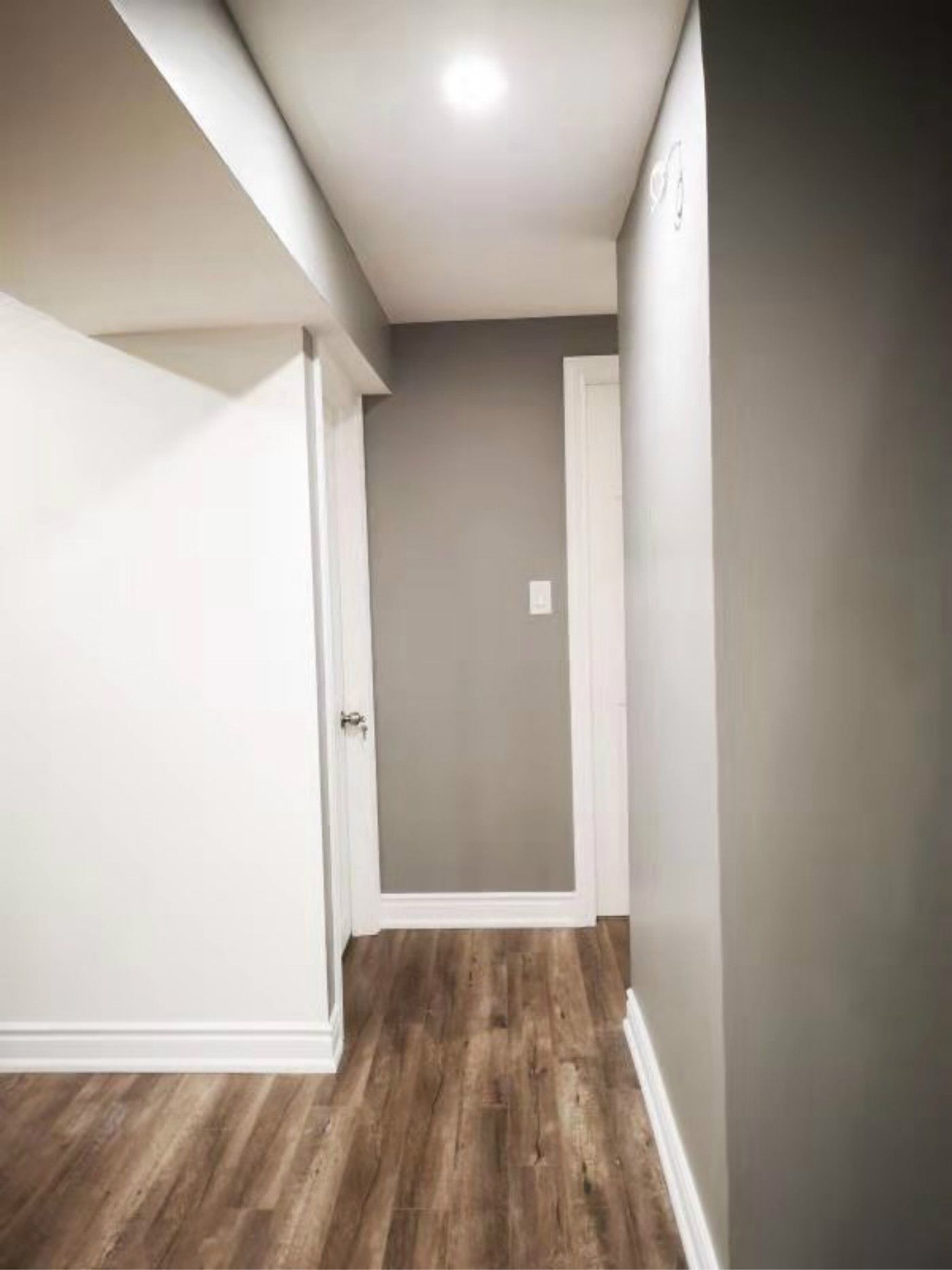This finished Mississauga basement hallway features clean wall finishes, modern vinyl flooring, and recessed lighting that enhances brightness and flow. The streamlined layout improves accessibility between rooms, showcasing the detailed work of a professional Toronto renovation company in creating a cohesive and functional basement design.