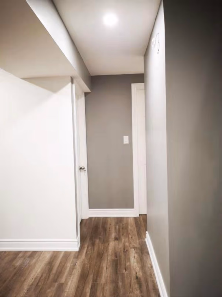This finished Mississauga basement hallway features clean wall finishes, modern vinyl flooring, and recessed lighting that enhances brightness and flow. The streamlined layout improves accessibility between rooms, showcasing the detailed work of a professional Toronto renovation company in creating a cohesive and functional basement design.
