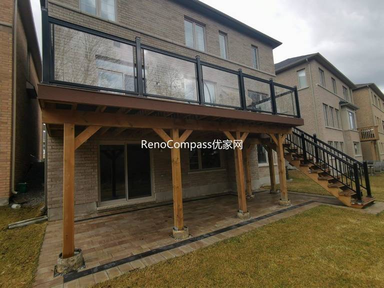 Custom elevated deck renovation in Aurora featuring composite decking, modern glass and aluminum railings, and a covered patio structure below. This professionally built outdoor space provides added functionality, weather protection, and a stylish backyard upgrade that enhances both usability and property value.