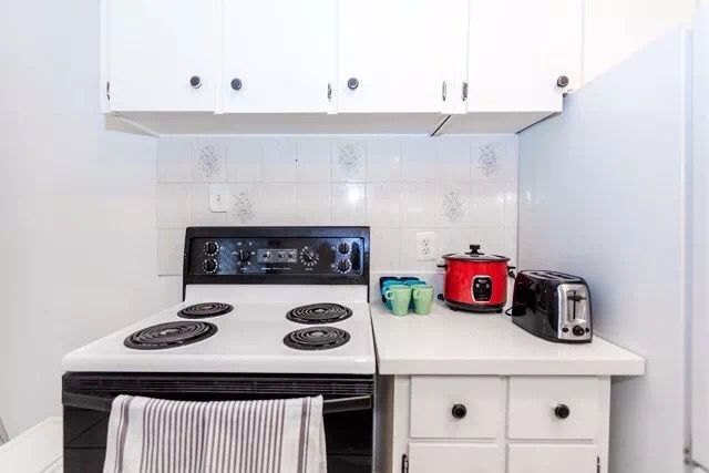 This Toronto interior renovation features a compact and functional kitchen layout with white cabinetry, classic tile backsplash, and modern appliances. The clean design maximizes space efficiency while maintaining a bright and organized cooking area. The renovation enhances both practicality and visual appeal, creating a comfortable kitchen environment suitable for everyday use in a Toronto home.