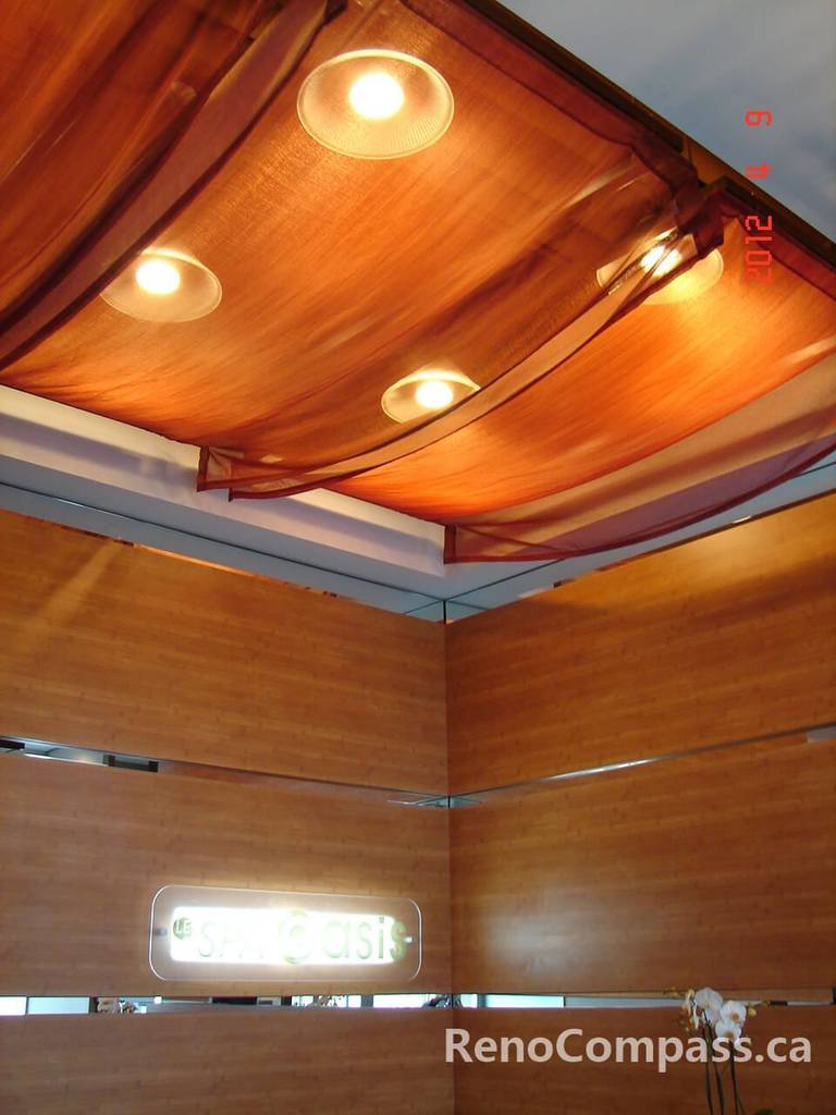 This Toronto beauty salon commercial renovation features a warm and inviting interior design with custom wood panel walls and a unique fabric ceiling installation. Recessed lighting enhances the ambiance while creating a relaxing, high-end spa environment for clients. Designed for both aesthetics and functionality, this commercial beauty space reflects modern salon design trends and professional craftsmanship by a trusted Toronto renovation company.
