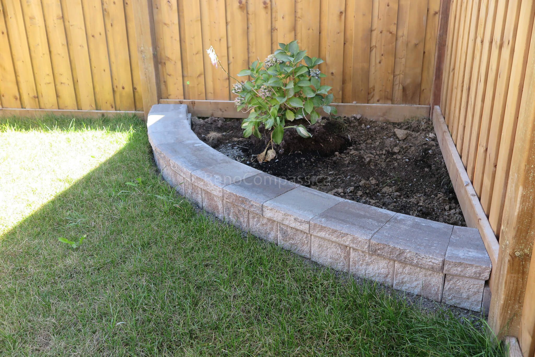 Custom curved garden bed and retaining wall completed in this Aurora backyard landscaping project. The stone border design creates a clean planting area against the wooden fence while maintaining a modern and low-maintenance outdoor layout. Professionally installed by Reno Compass Inc., a trusted Toronto landscaping and renovation contractor serving Aurora and the GTA.