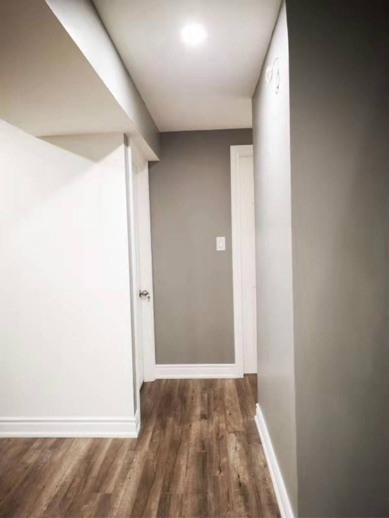 This finished Mississauga basement hallway features clean wall finishes, modern vinyl flooring, and recessed lighting that enhances brightness and flow. The streamlined layout improves accessibility between rooms, showcasing the detailed work of a professional Toronto renovation company in creating a cohesive and functional basement design.