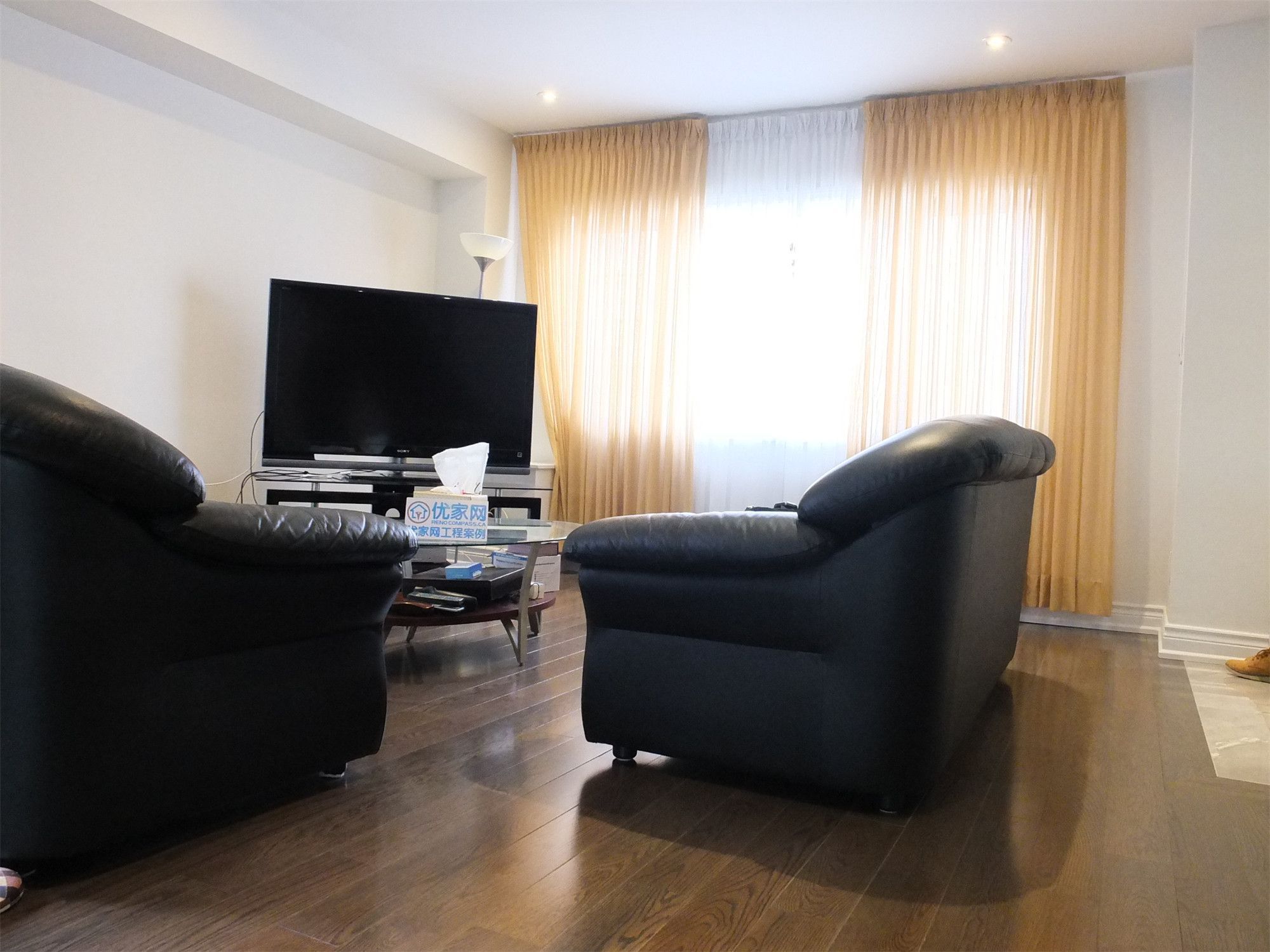 Comfortable living room space from a Scarborough home addition project featuring dark hardwood flooring, large window with natural light, and a cozy seating area. The renovation creates a warm and functional gathering space within the newly expanded home layout.
