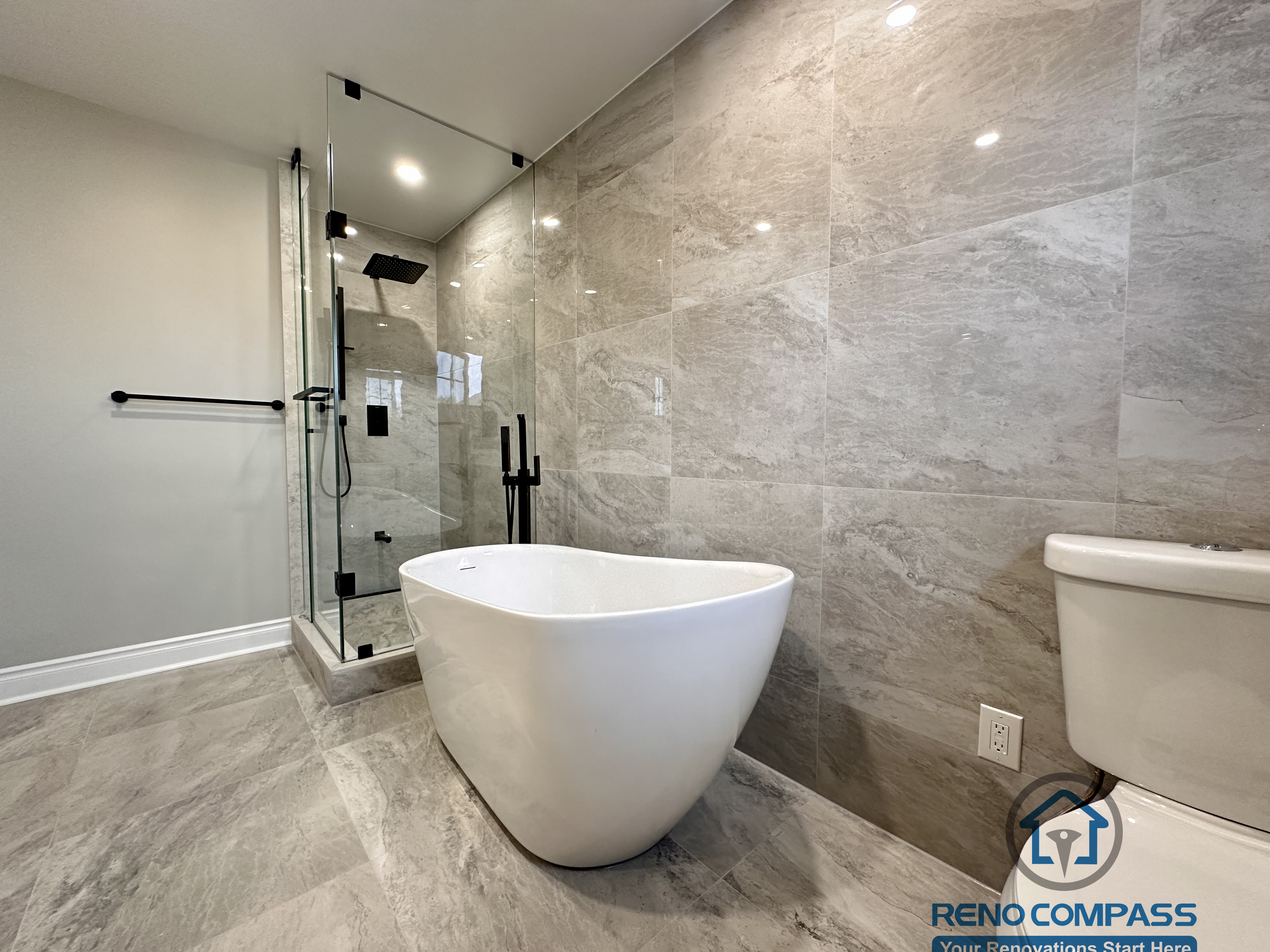 This Markham bathroom renovation features a modern layout with a freestanding bathtub, glass-enclosed shower, and large-format stone-look tiles. Designed and built by a professional Toronto renovation company, Reno Compass Inc., the space balances functionality, clean lines, and long-term durability.