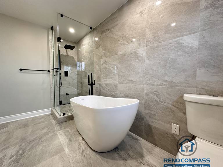 This Markham bathroom renovation features a modern layout with a freestanding bathtub, glass-enclosed shower, and large-format stone-look tiles. Designed and built by a professional Toronto renovation company, Reno Compass Inc., the space balances functionality, clean lines, and long-term durability.