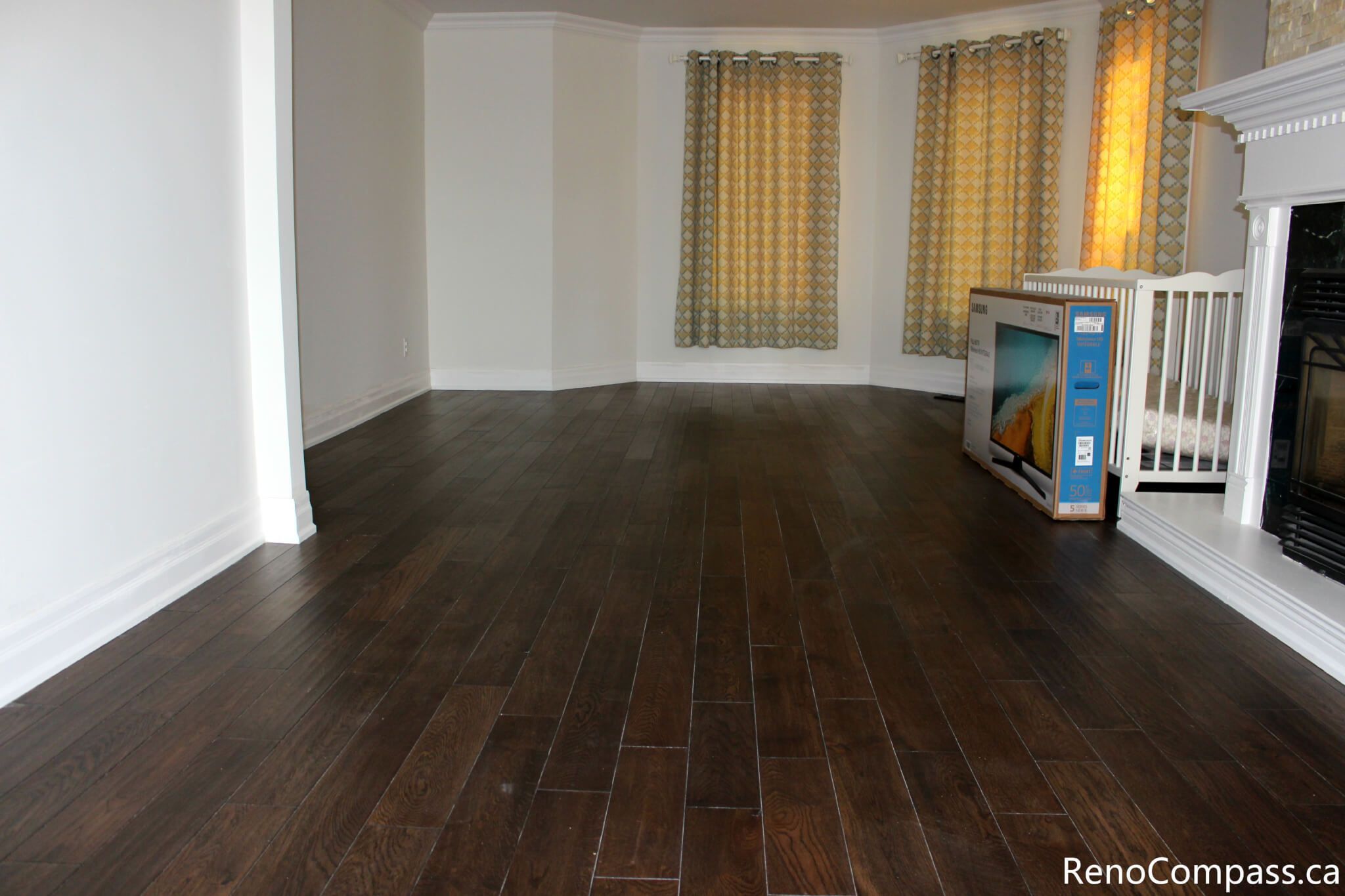 This Mississauga interior renovation showcases a spacious living area upgraded with premium dark hardwood flooring, fresh modern wall finishes, and enhanced natural lighting through large windows with custom curtains. The renovation improves comfort, durability, and overall home value while creating a warm and elegant living space. Completed by a professional Toronto renovation company, Reno Compass Inc., this project highlights quality craftsmanship and refined interior finishing.