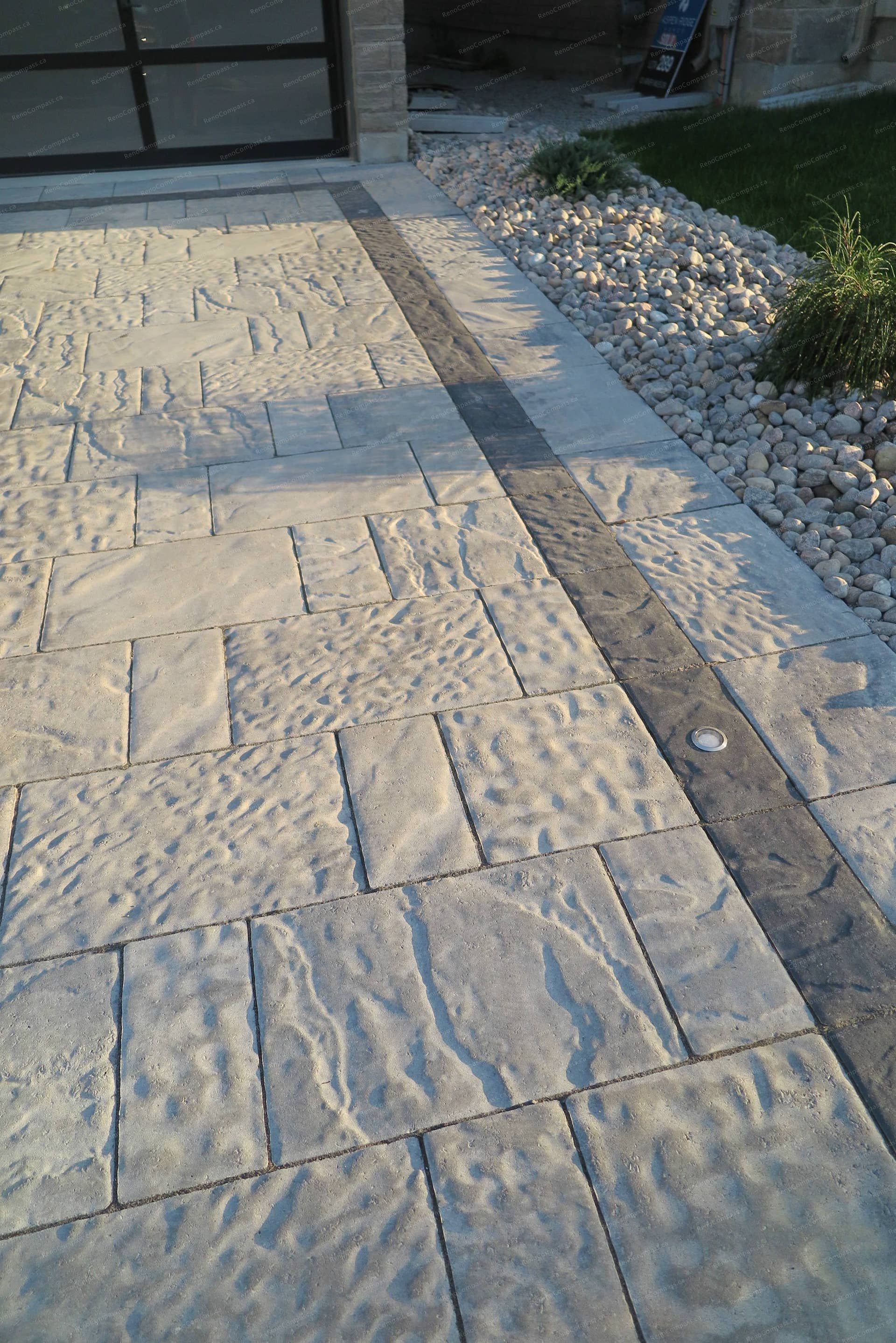 Stamped concrete driveway renovation for a detached home in Vaughan featuring natural stone texture patterns and a contrasting decorative border. This front yard hardscaping design provides a durable, low-maintenance driveway while enhancing the property’s modern curb appeal and overall landscape layout.