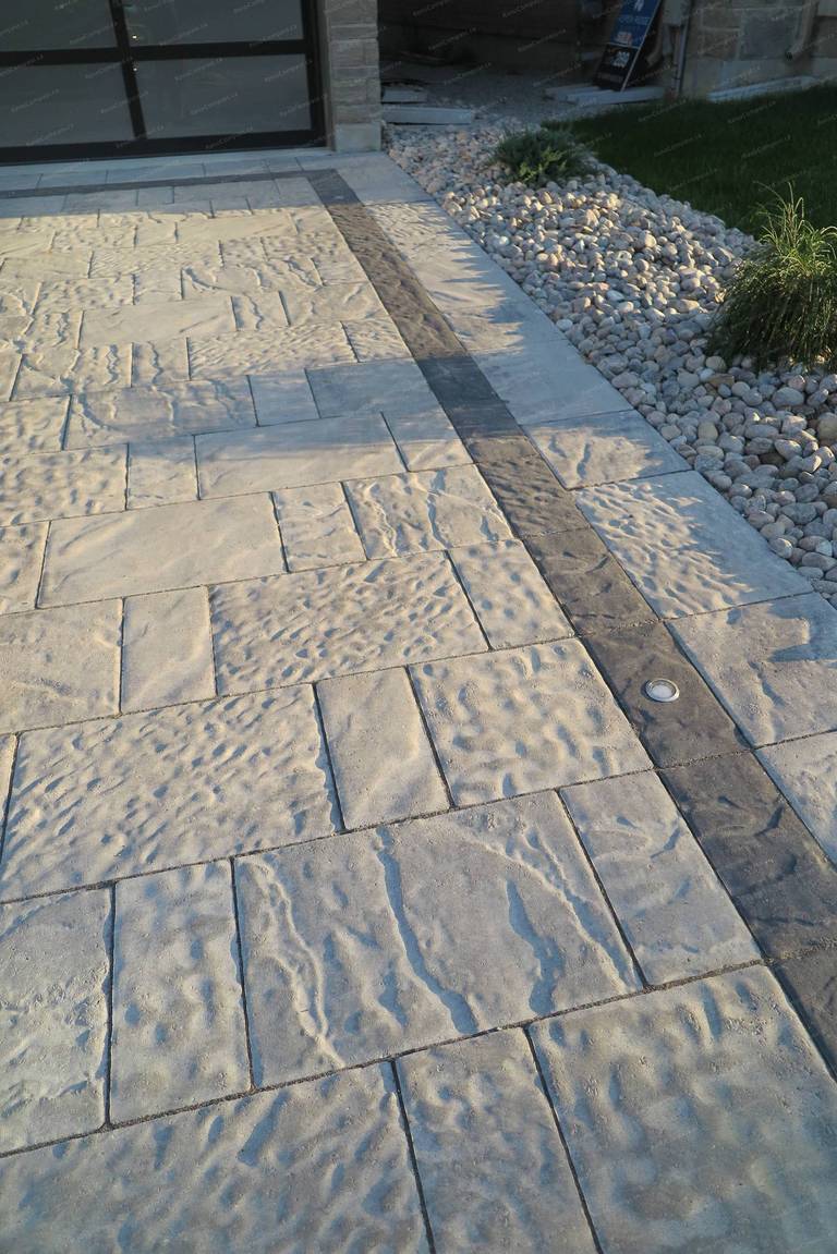 Stamped concrete driveway renovation for a detached home in Vaughan featuring natural stone texture patterns and a contrasting decorative border. This front yard hardscaping design provides a durable, low-maintenance driveway while enhancing the property’s modern curb appeal and overall landscape layout.