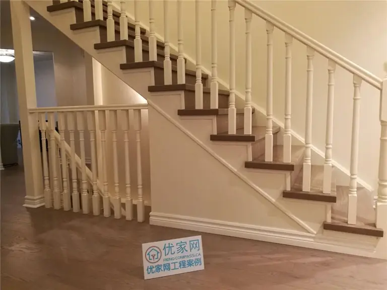 This image presents a side profile view of a completed staircase flooring renovation in North York, highlighting hardwood stair treads paired with white railings and balusters. The clean lines of the staircase structure and the consistent wood flooring across the lower level create a cohesive and polished interior appearance. Careful detailing at the stair stringer and baseboard transitions enhances both durability and visual balance. This North York flooring renovation showcases precise installation and craftsmanship by a professional Toronto renovation company specializing in residential flooring and staircase renovations.