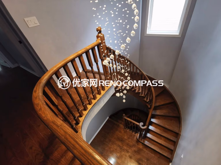 Richmond Hill interior renovation featuring a curved solid wood staircase with custom railings and a modern cascading chandelier. The upgraded stairwell design enhances natural light, architectural elegance, and overall home value, completed by a professional Toronto renovation company.