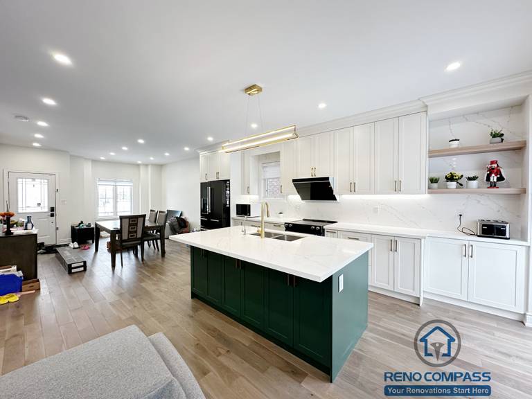Interior renovation in Markham showcasing a modern kitchen with custom white cabinetry, a contrasting dark green island, quartz countertops, and integrated lighting. The open layout enhances functionality, flow, and everyday family use.