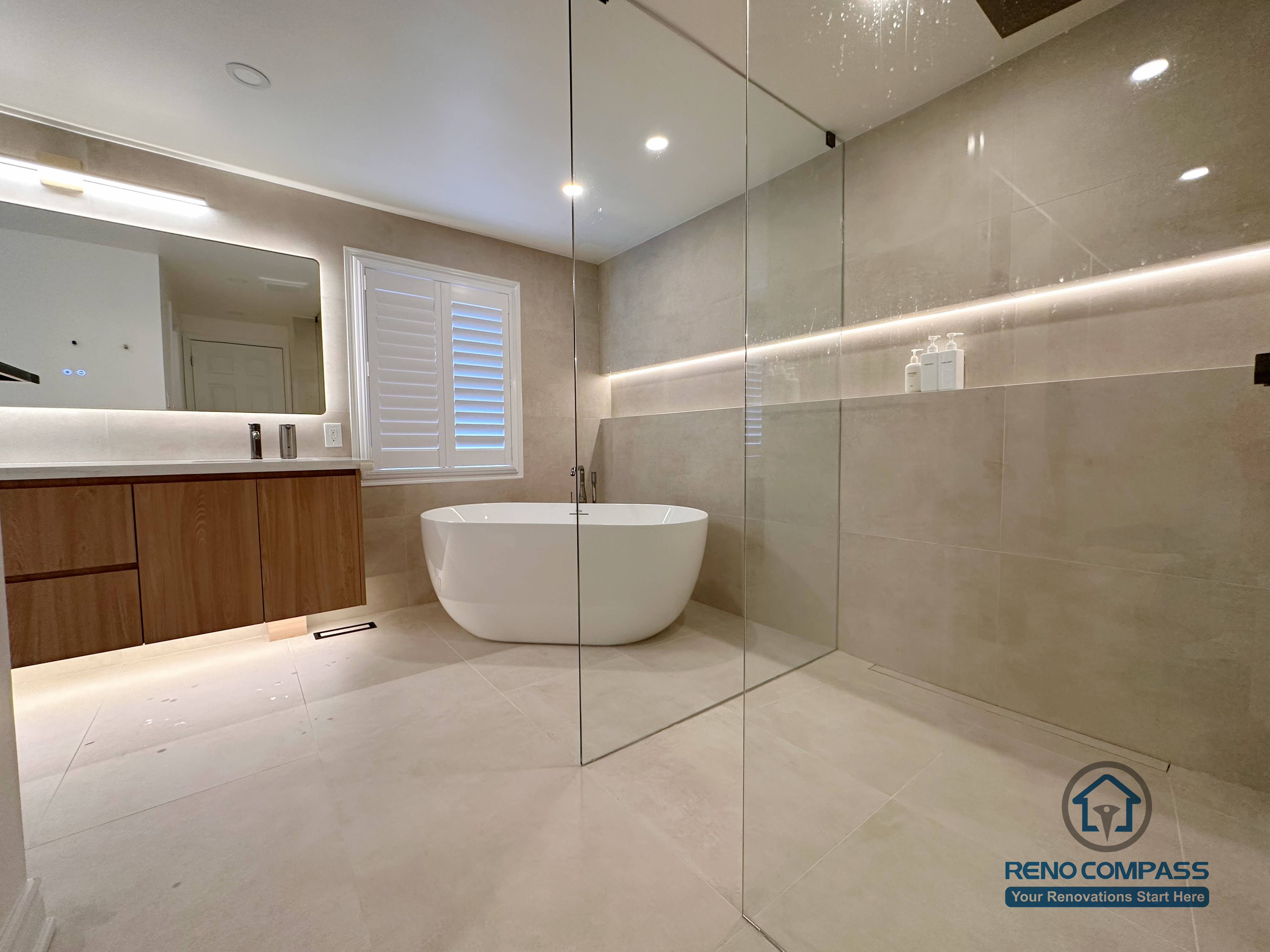 This Markham accessible bathroom renovation features a freestanding bathtub positioned within a barrier-free layout, allowing easy movement and step-free access. Large-format floor and wall tiles, integrated linear lighting, and a custom wood-tone vanity contribute to a calm, safe, and modern environment. Designed and built by a professional Toronto renovation company, Reno Compass Inc., the space prioritizes accessibility, comfort, and long-term usability.