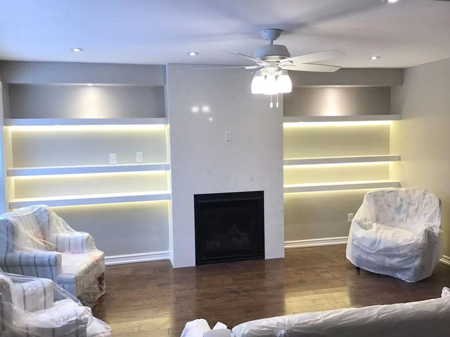 This Richmond Hill interior partial renovation highlights a modern living room upgrade featuring a custom fireplace feature wall with built-in illuminated shelving on both sides. Warm LED lighting enhances the display areas while creating a cozy and elegant ambiance. The renovated space includes upgraded flooring, recessed ceiling lights, and a clean contemporary layout designed for comfort and functionality. Completed by Reno Compass, this interior remodeling project adds both visual appeal and practical storage solutions, showcasing high-quality craftsmanship for homes across Richmond Hill and the Greater Toronto Area.