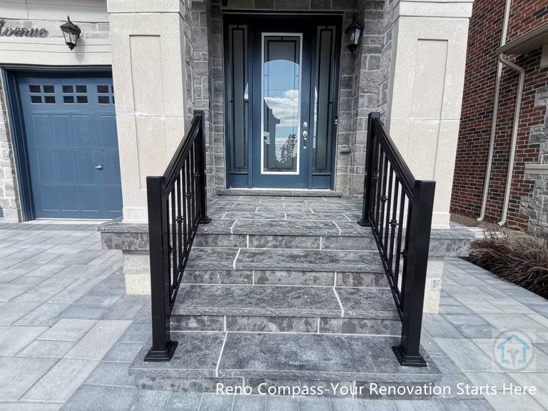 This Vaughan front entrance renovation highlights custom stone steps and a structured walkway leading to the main door. The natural stone finish, clean joint lines, and black metal railings create a refined and durable entry experience that seamlessly connects the driveway with the home’s front façade.