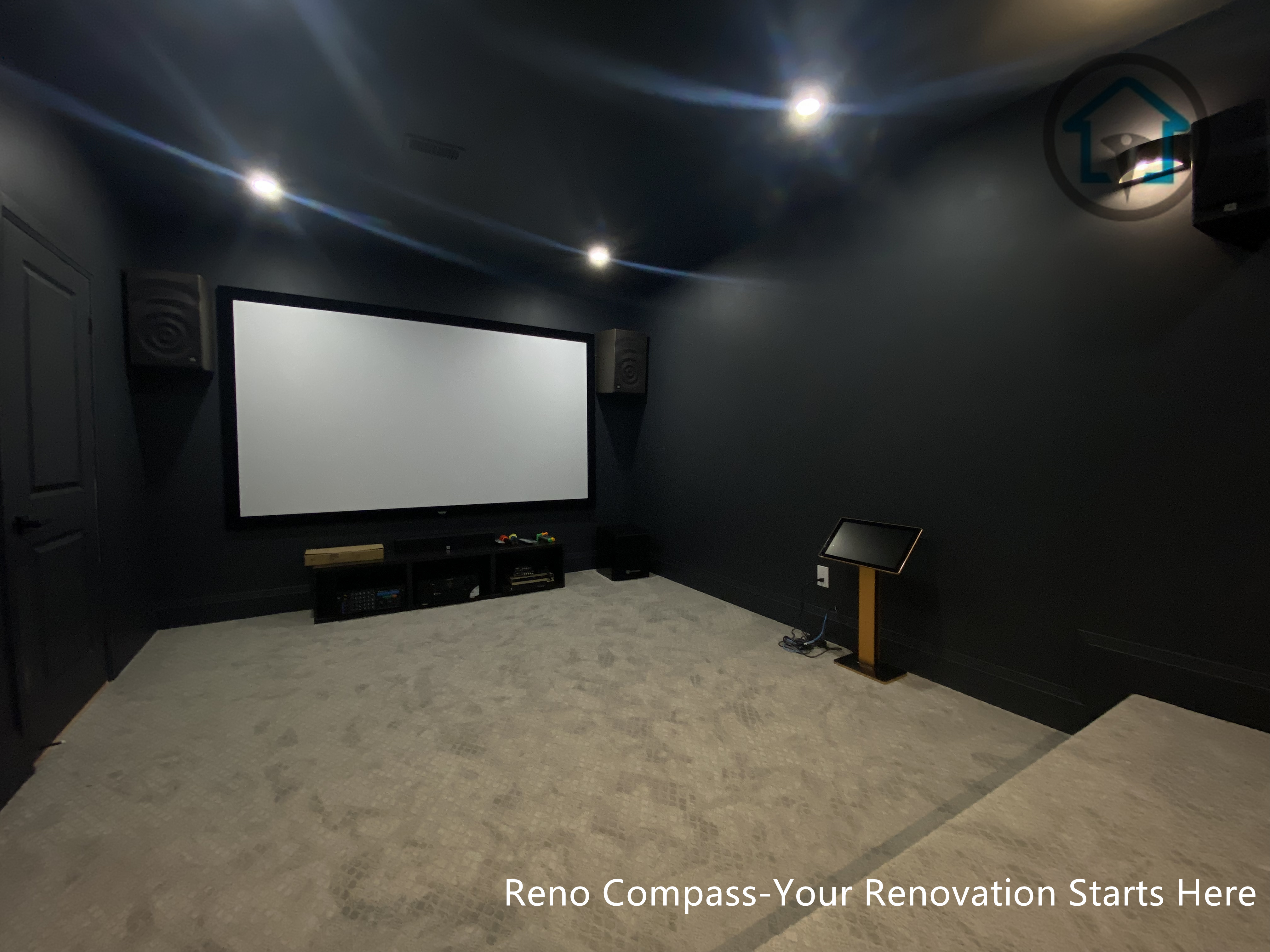 This image features a custom basement home theater renovation in Richmond Hill, designed with dark wall finishes, wall-mounted ambient lighting, and a raised platform for optimal viewing experience. The enclosed layout enhances sound control and visual focus, creating a private cinematic environment within the home. Completed by Reno Compass, this home theater renovation demonstrates thoughtful space planning and lighting design tailored for immersive entertainment in a modern basement setting.