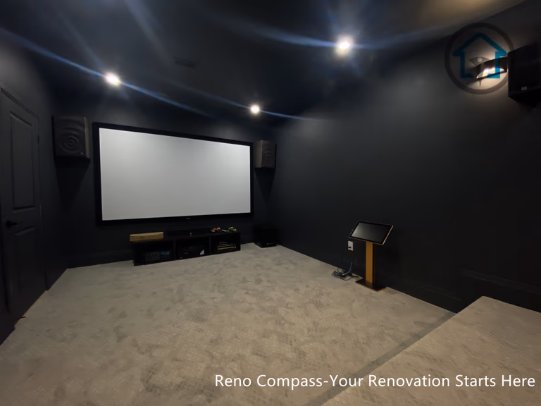This image features a custom basement home theater renovation in Richmond Hill, designed with dark wall finishes, wall-mounted ambient lighting, and a raised platform for optimal viewing experience. The enclosed layout enhances sound control and visual focus, creating a private cinematic environment within the home. Completed by Reno Compass, this home theater renovation demonstrates thoughtful space planning and lighting design tailored for immersive entertainment in a modern basement setting.