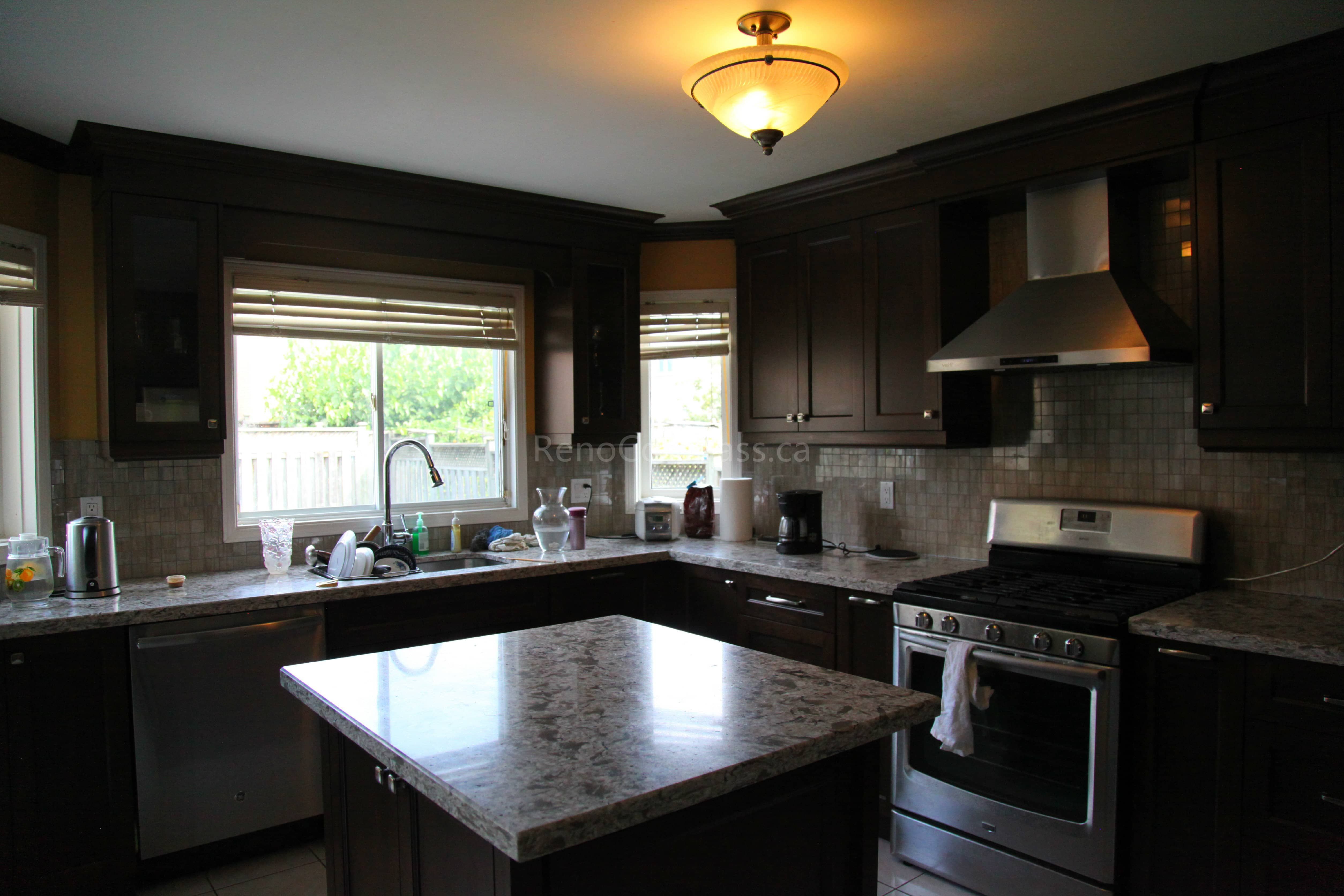 This Markham kitchen renovation features rich dark wood cabinetry, a custom quartz island, and modern stainless steel appliances, creating a warm and functional cooking space. Designed and completed by a professional Toronto renovation company, the layout enhances storage, workflow, and overall visual appeal while maintaining a timeless and elegant kitchen design.