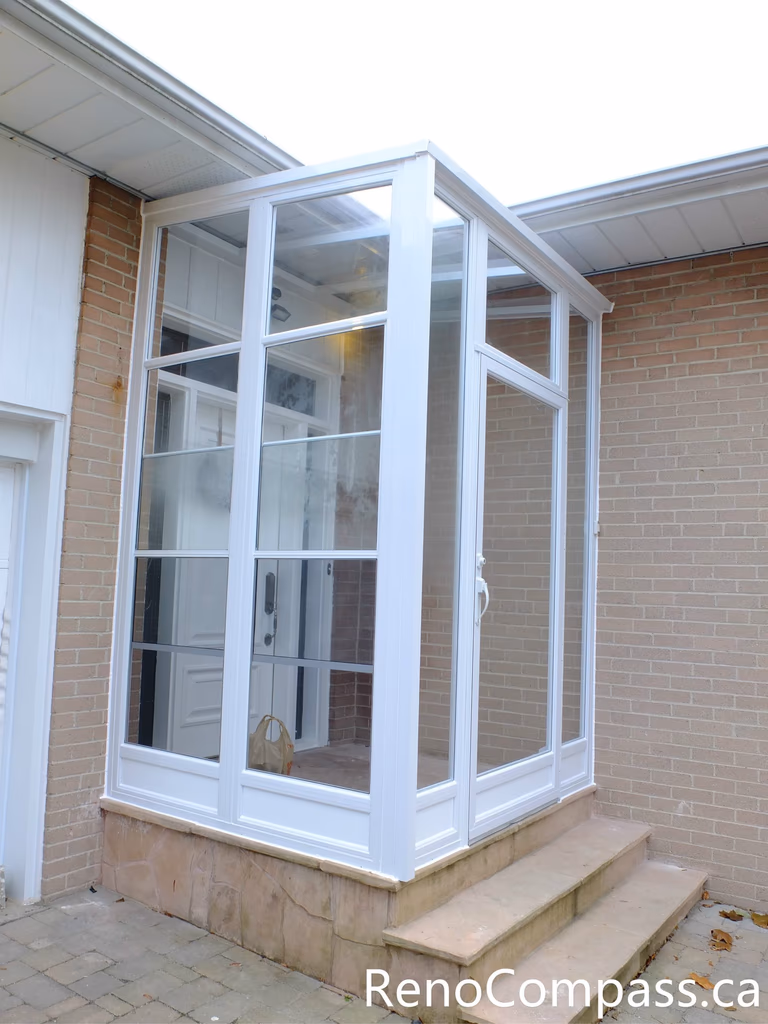 This North York home entrance renovation features a custom glass storm door vestibule designed to improve insulation, weather protection, and curb appeal. The bright white frame and full-height glass panels create a clean, modern look while allowing natural light to enter the entryway. This type of enclosed front entrance helps protect the main door from harsh Canadian weather and improves energy efficiency. Completed by a professional Toronto renovation team, the project enhances both functionality and visual appeal for the homeowner.