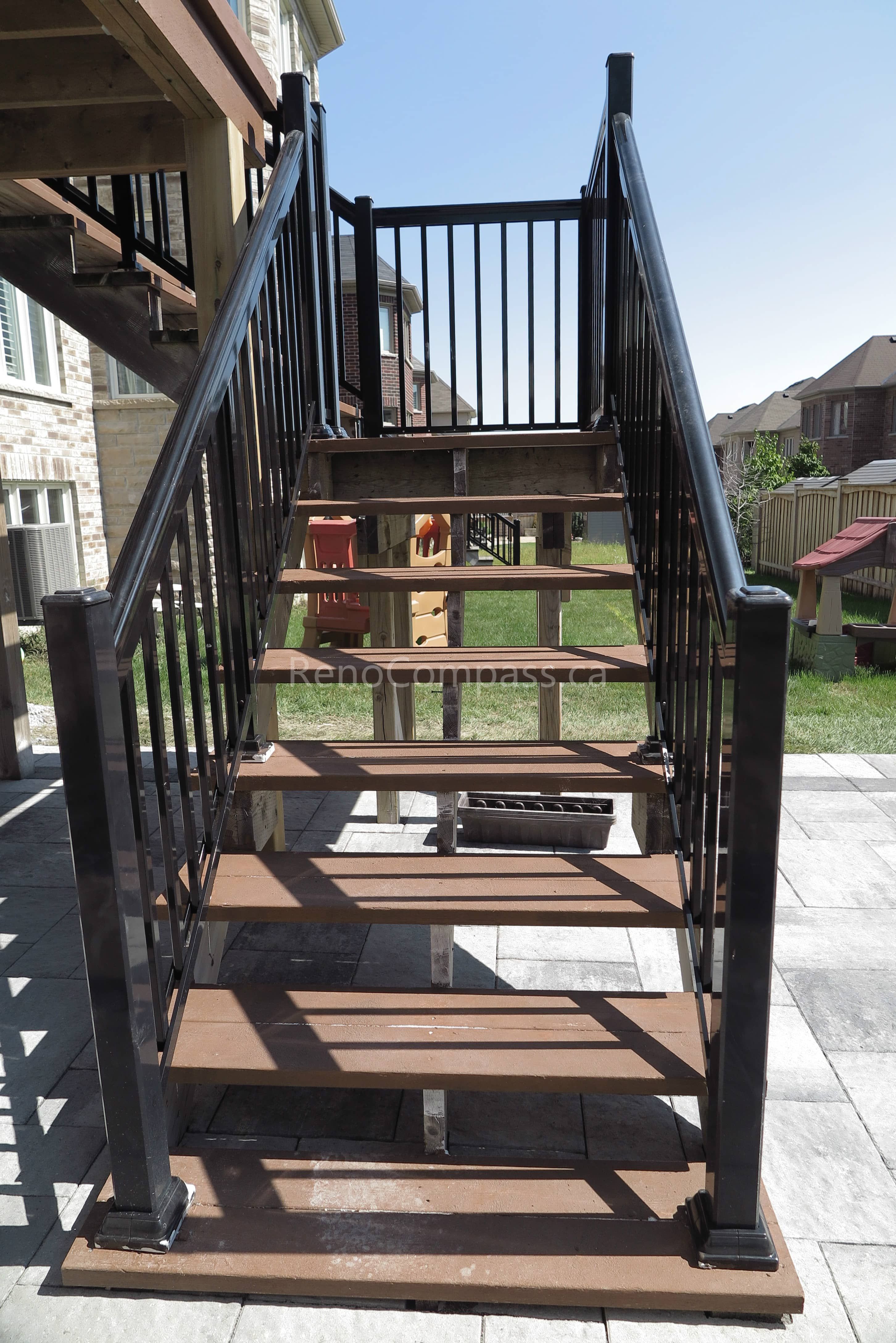 This Markham landscaping renovation showcases a custom-built elevated wooden deck with modern black aluminum railings and staircase, paired with a newly installed interlock stone patio below. The upgraded backyard design enhances outdoor living with a functional multi-level entertainment space, improved accessibility, and a clean contemporary look. Completed by Reno Compass, this project blends durable craftsmanship with stylish landscaping to create a comfortable and inviting backyard environment for homeowners.
