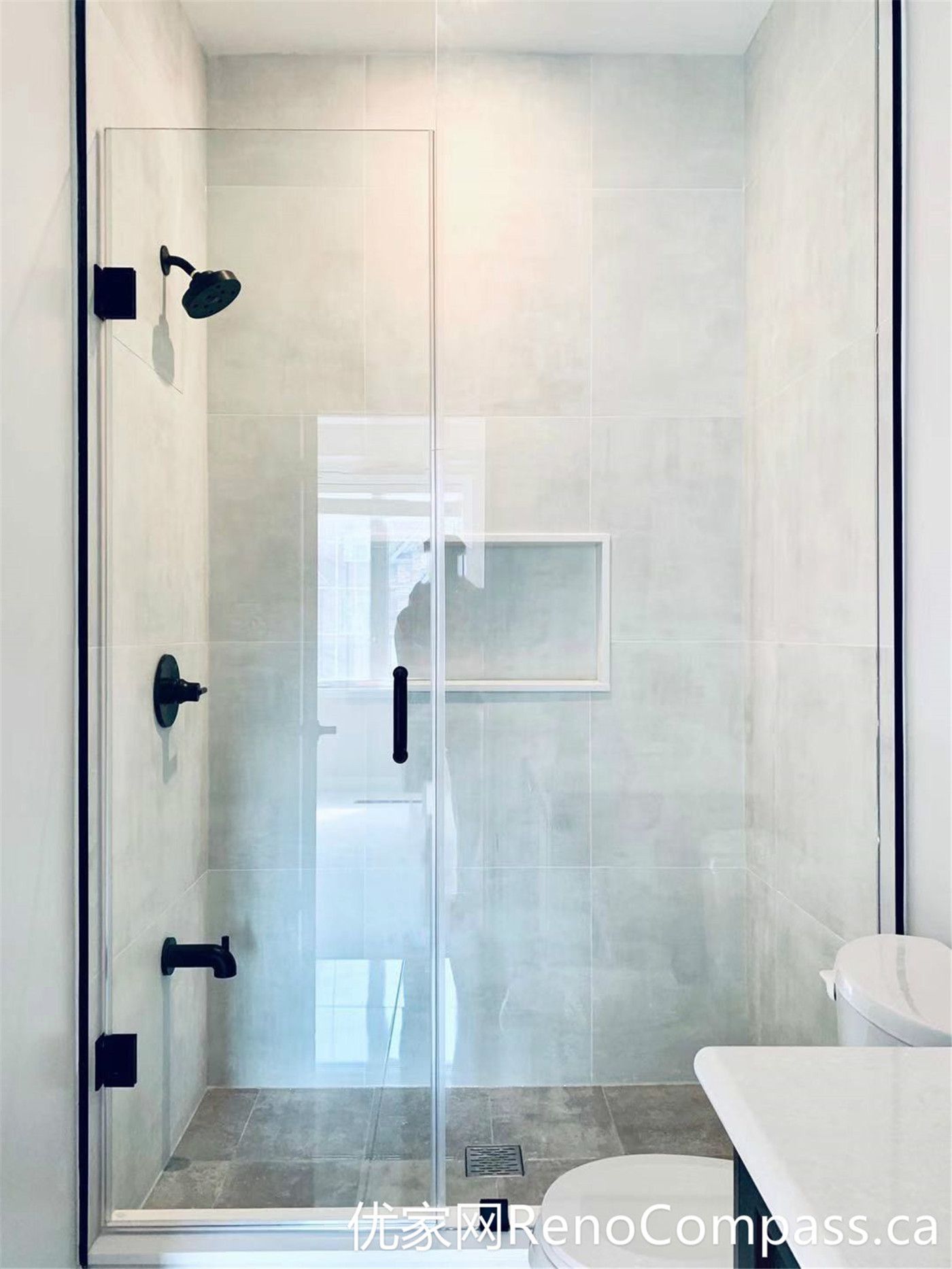 This walk-in shower from a Markham home renovation features a frameless glass enclosure, matte black fixtures, and a built-in wall niche for convenient storage. The neutral tile design and clean layout provide a modern, low-maintenance solution that balances style and everyday functionality.