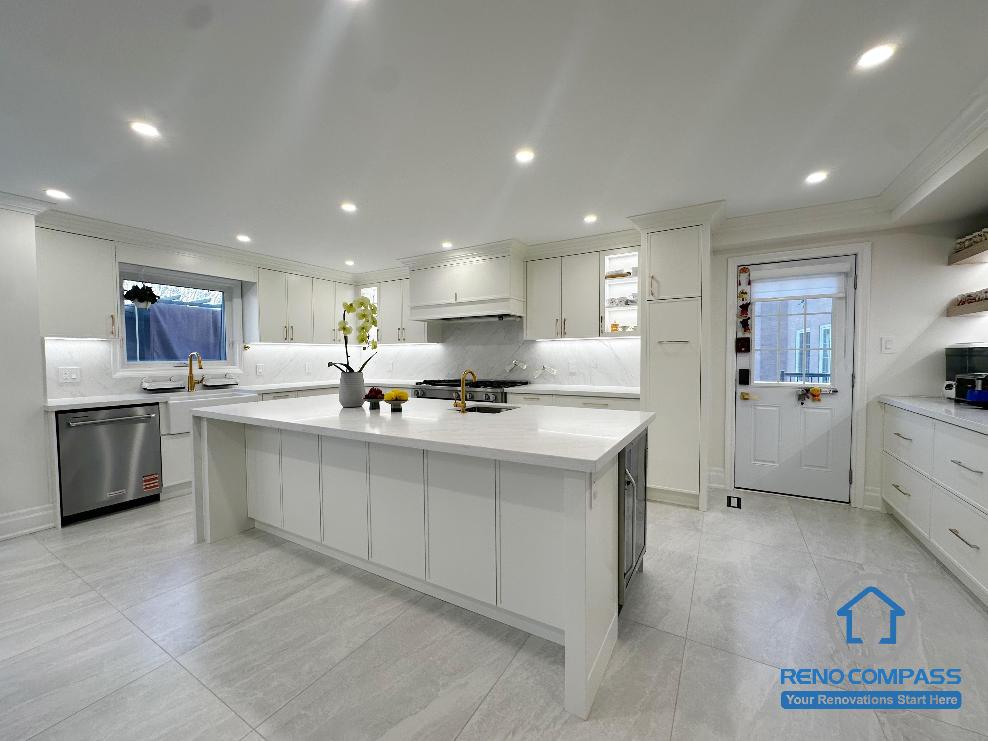 This kitchen renovation features a bright, open layout centered around a large island that enhances both functionality and flow. Custom white cabinetry, quartz countertops, and integrated appliances create a clean, cohesive look, while recessed ceiling lighting ensures even illumination throughout the space. The design balances everyday usability with a timeless, modern aesthetic.