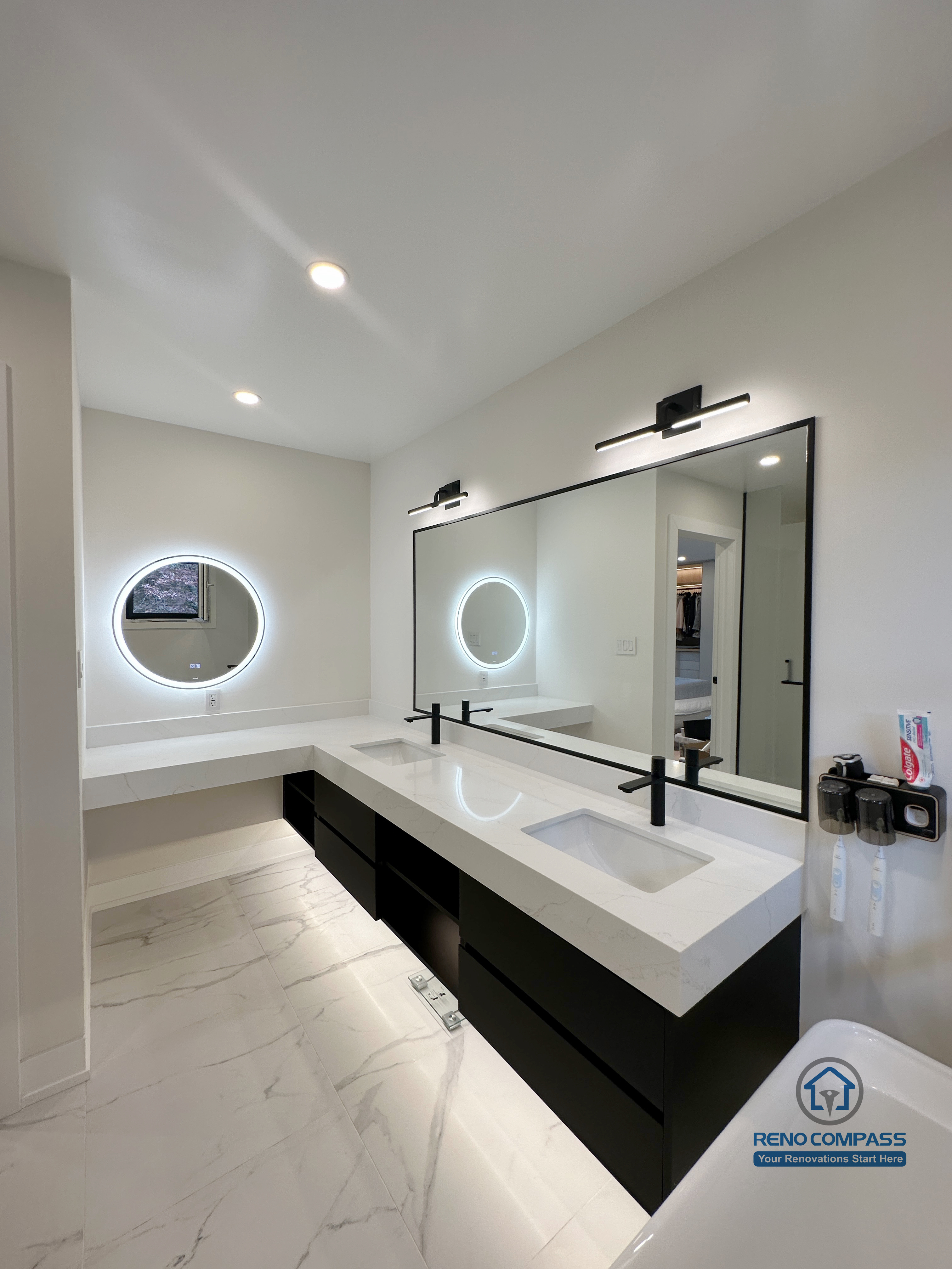 Modern bathroom renovation in Toronto highlighting a custom-built vanity, integrated LED mirror lighting, sleek countertop sink, matte black faucets, and marble-look porcelain flooring. Designed and completed by a professional Toronto renovation company with a focus on lighting, functionality, and contemporary aesthetics.
