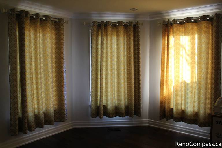 This Mississauga interior renovation highlights a bright bay window living space enhanced with custom curtain installation, detailed trim work, and rich hardwood flooring. The upgraded windows improve natural light control while adding warmth and elegance to the room. Completed by a trusted Toronto renovation company, Reno Compass Inc., this project showcases refined interior finishing and professional craftsmanship.